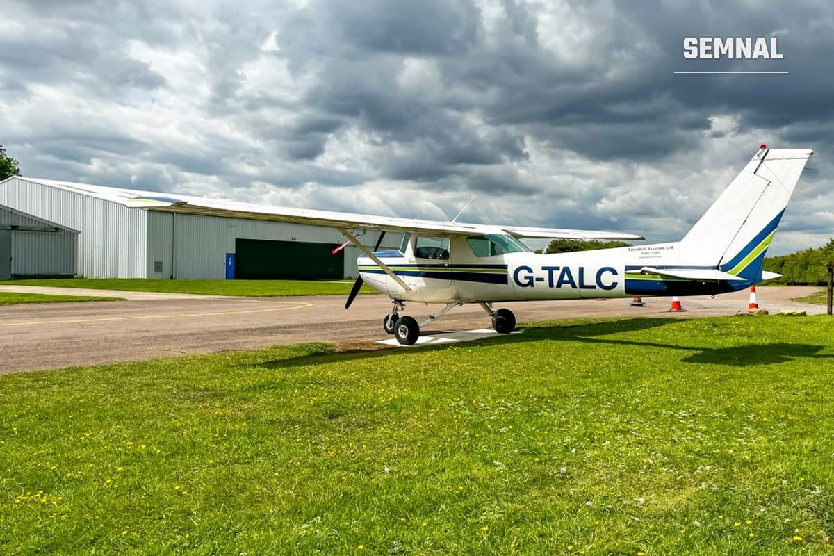 Avion ușor pe iarbă lângă un hangar, imagine ilustrativă