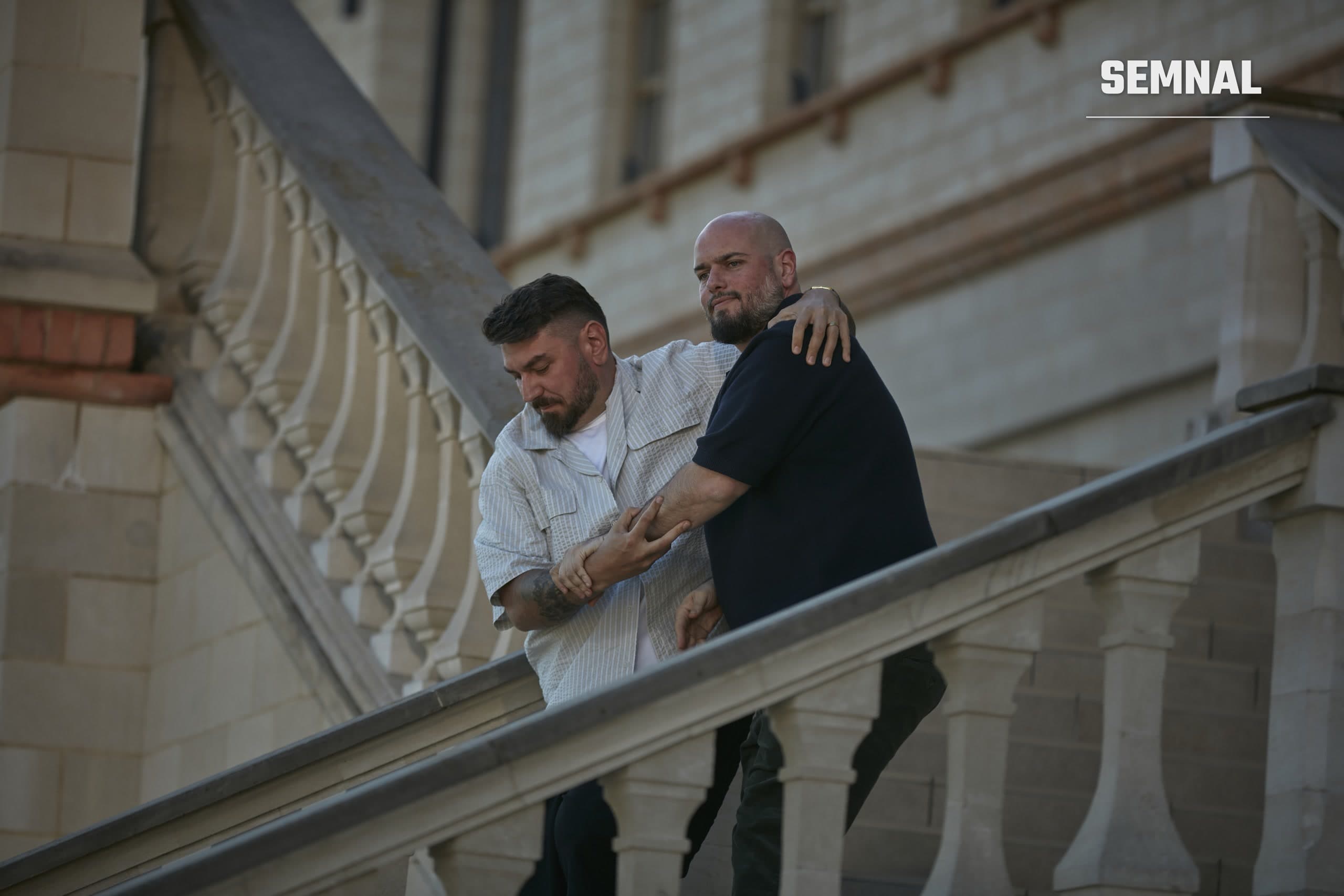 Doi bărbați îmbrățișați coboară scara de piatră a unui castel, într-o scenă din filmul Teambuilding 2