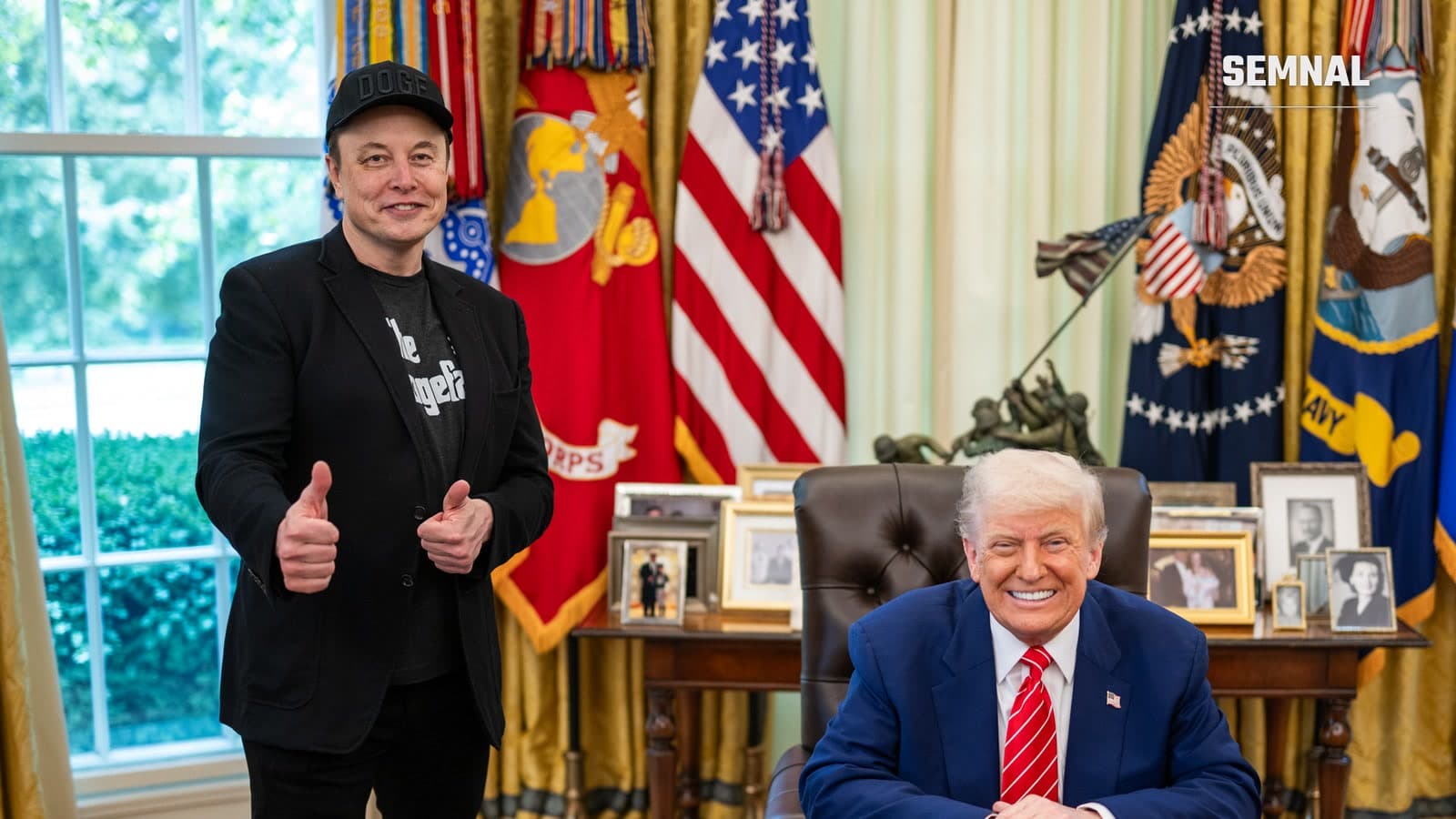 Elon Musk, în picioare, cu degetele mari ridicate, și Donald Trump, zâmbind la birou, în Biroul Oval de la Casa Albă, într-o fotografie oficială din mai 2025