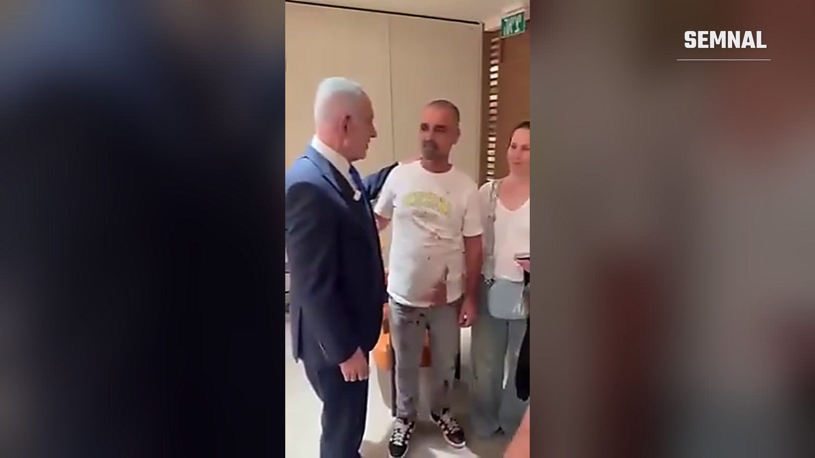 Benjamin Netanyahu stă de vorbă cu pasagerul Yaniv Hayun, cu tricoul pătat de sânge, pe aeroportul Ben Gurion