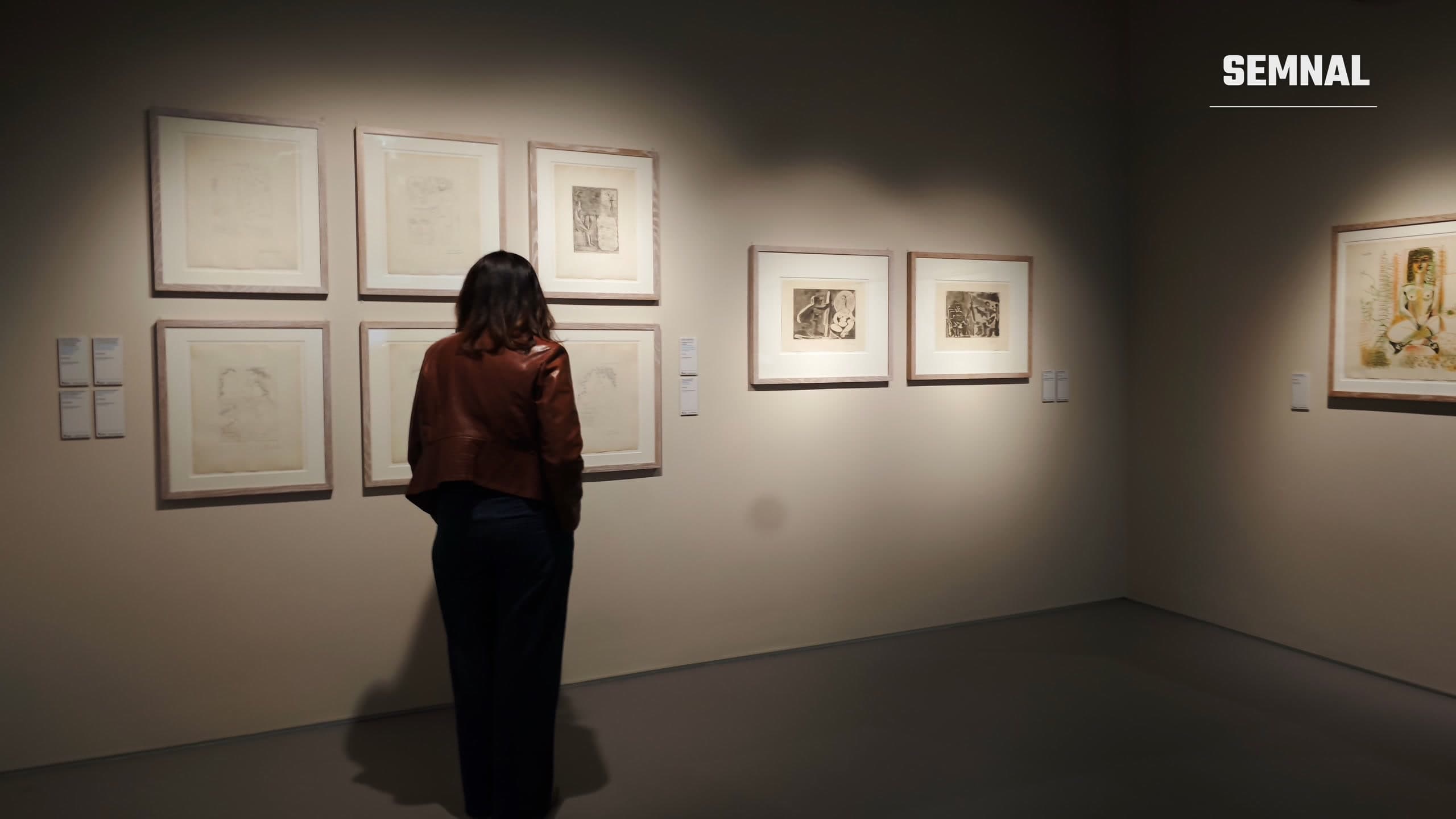 Vizitatoare privind de aproape gravurile lui Pablo Picasso expuse pe un perete la Art Encounters din Timișoara