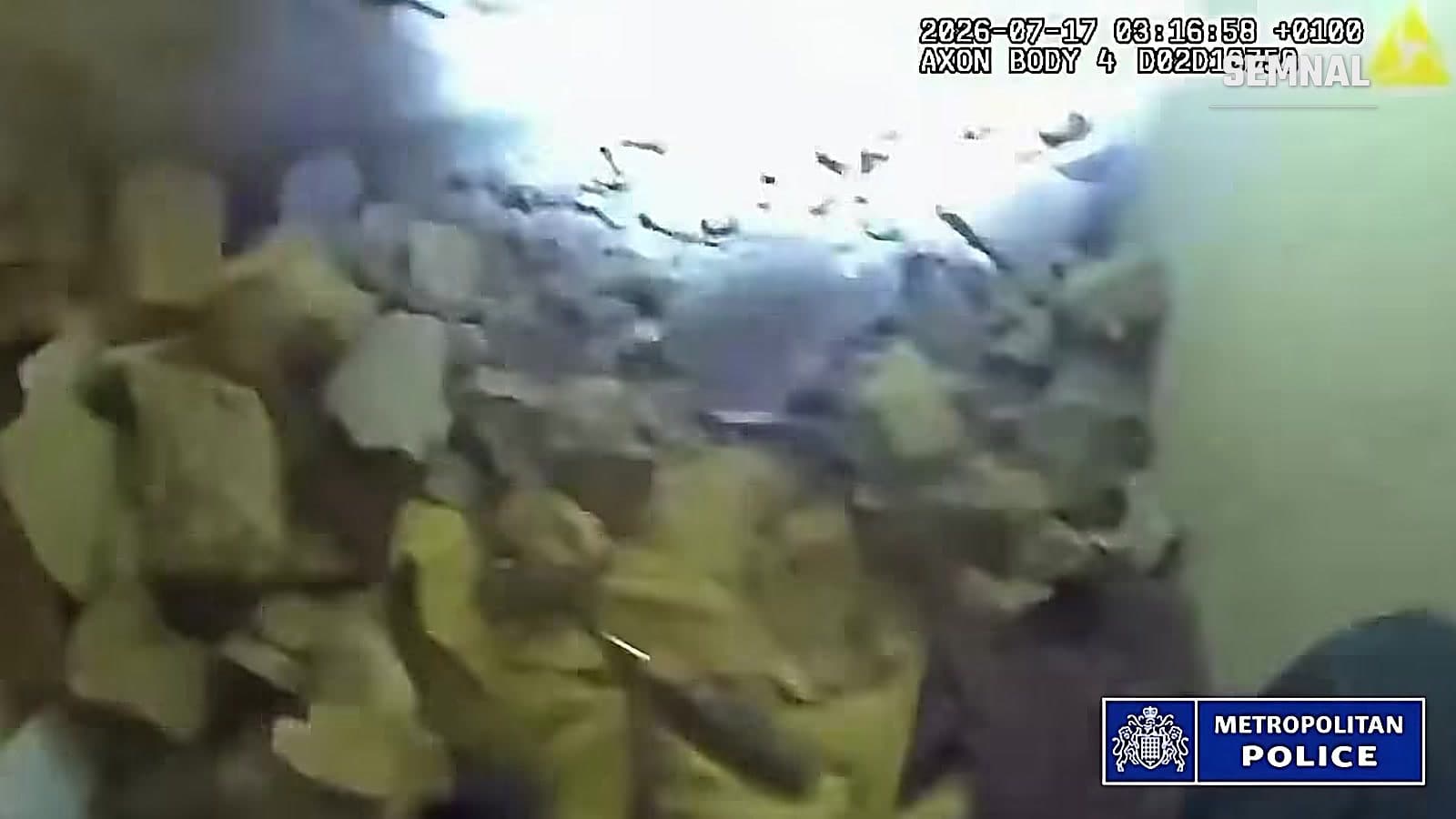Moloz și cărămizi sparte lângă gaura săpată în peretele unui salon de masaj din Tooting, Londra, filmate de camera de corp a unui polițist
