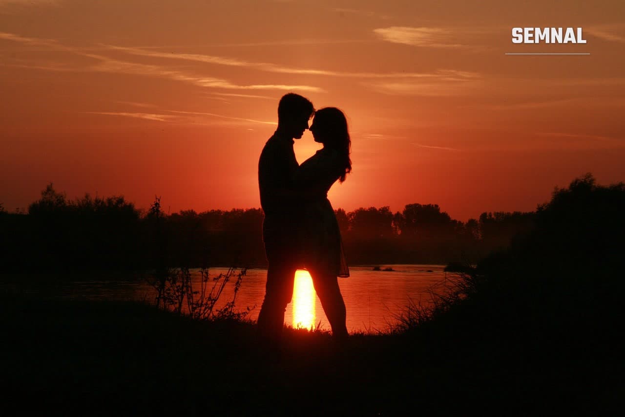 Siluetă a unui cuplu care se privește față în față, pe fundalul unui apus roșu (Foto: AdinaVoicu / Pixabay)