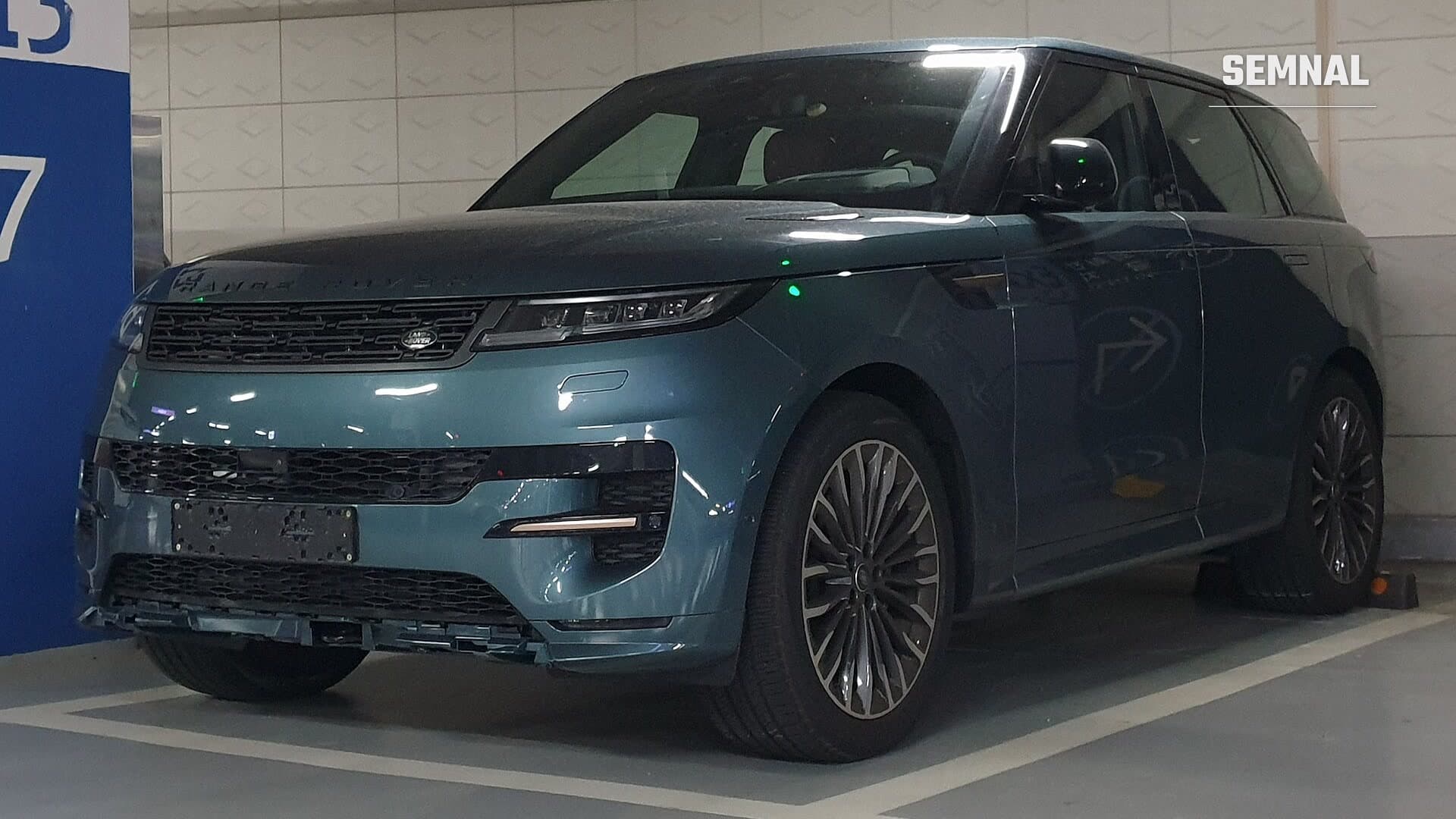 Range Rover Sport de generația L461, în albastru-verzui, văzut din față și din lateral într-o parcare subterană