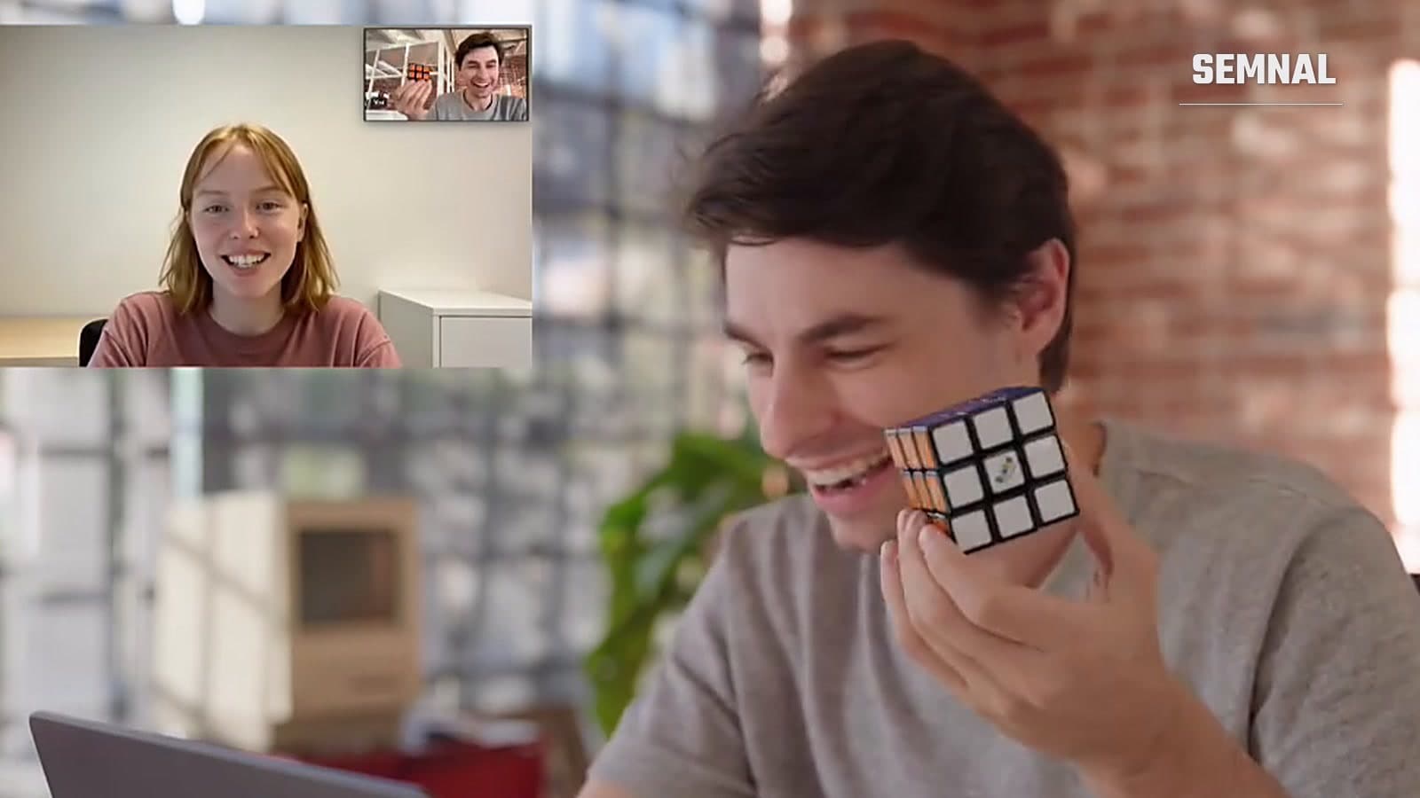 Bărbat care ține un cub Rubik rezolvat, în apel video cu avatarul AI Griffin, care apare în colțul ecranului