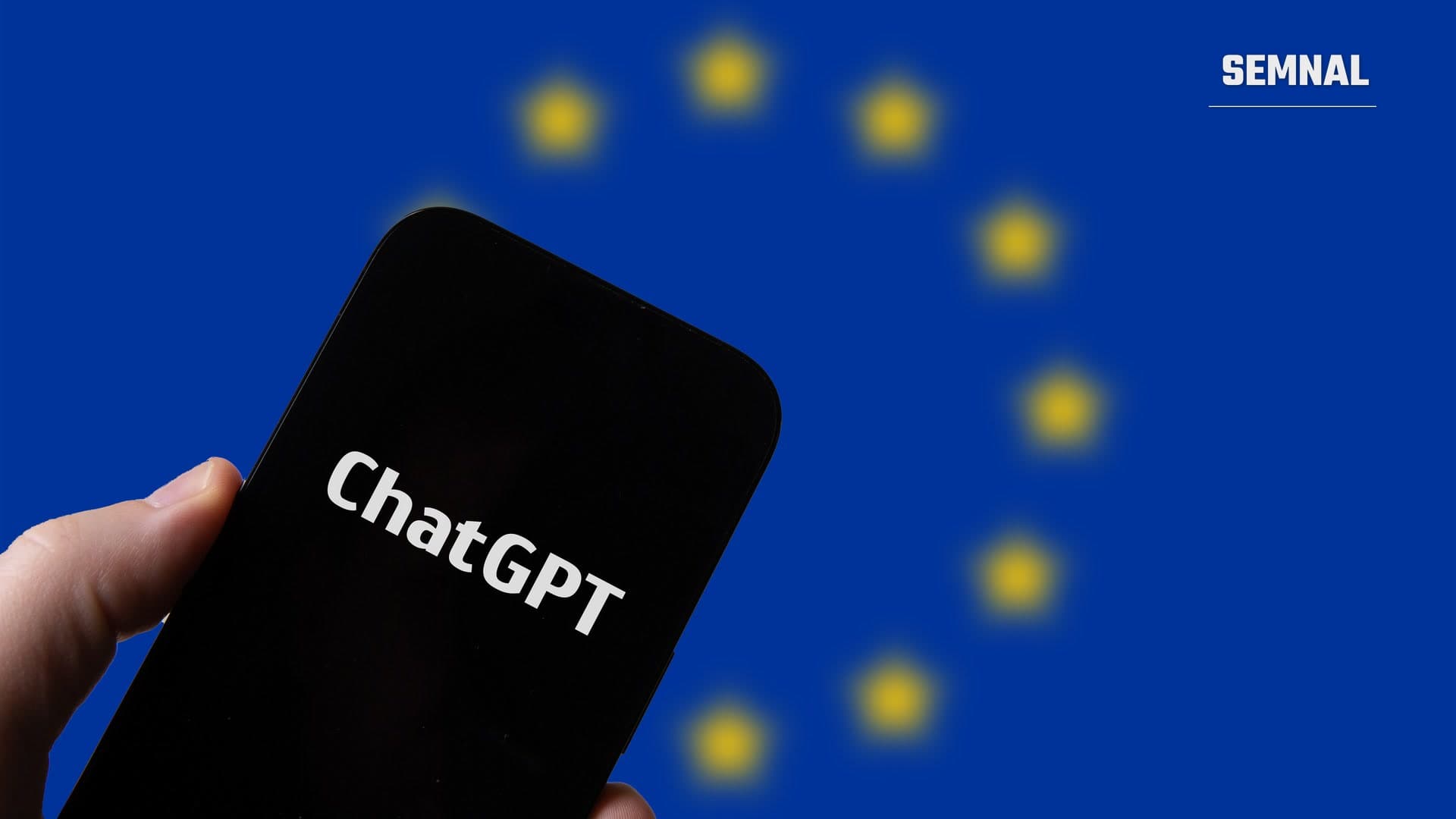 Mână care ține un telefon cu sigla ChatGPT pe ecran, în fața unui drapel albastru al Uniunii Europene cu stele galbene, estompate (Foto: Jernej Furman / Wikimedia Commons, CC BY 2.0)