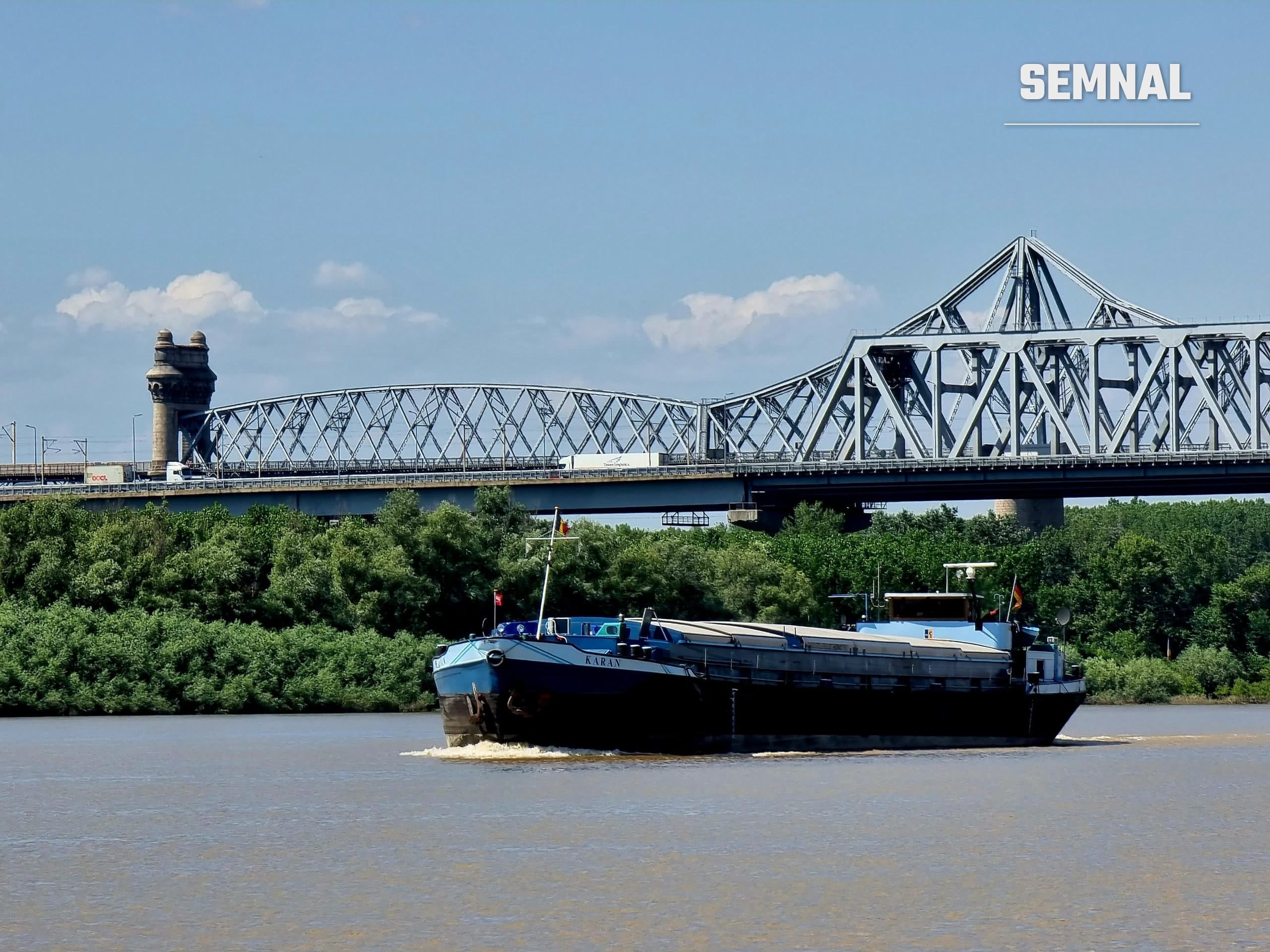 Barjă de transport fluvial navigând pe Dunăre la Cernavodă, cu podul Anghel Saligny și podul rutier în fundal (Foto: Semnal)