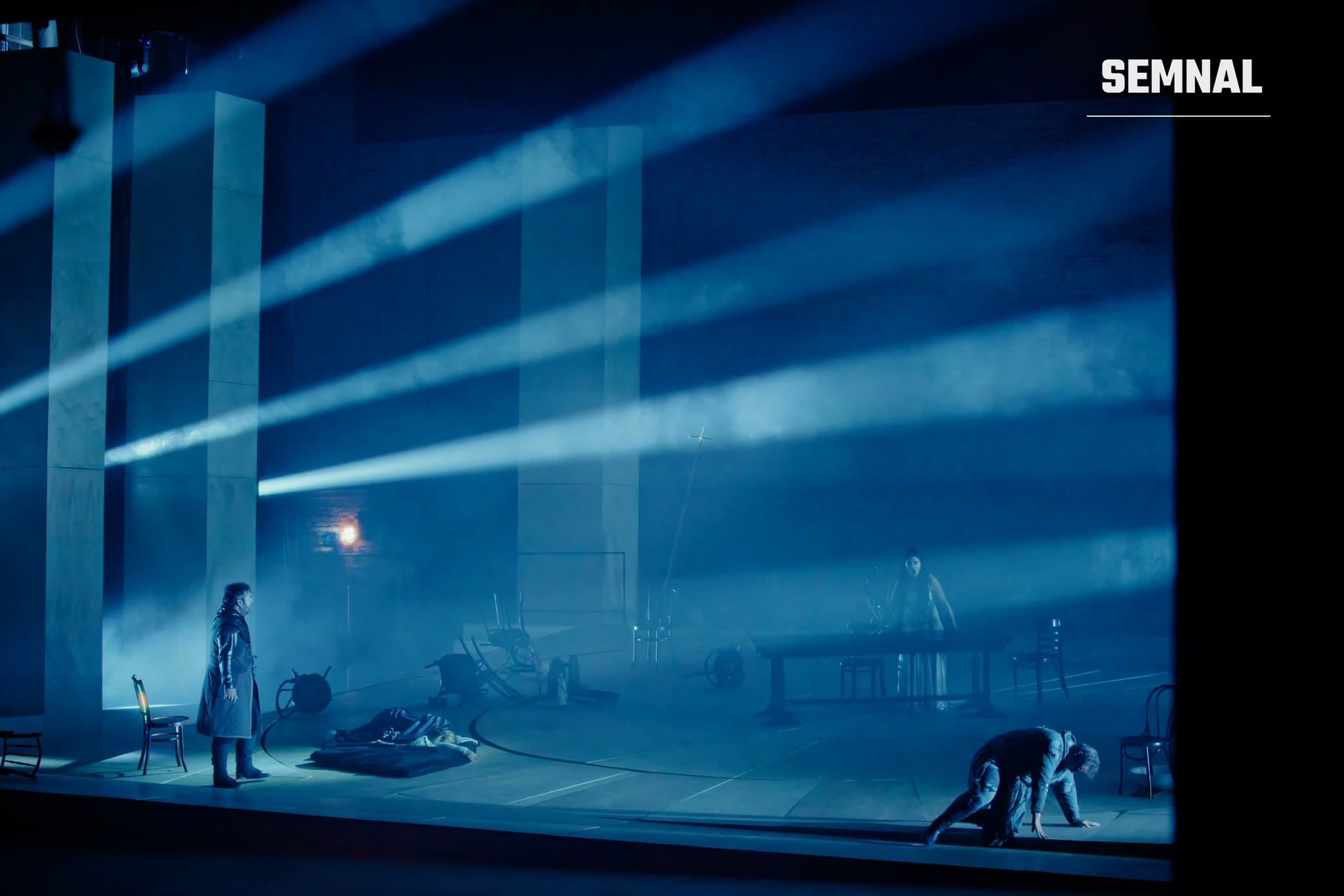 Scenă din spectacolul „Tannhäuser” de Wagner la Opera Națională București, cu fascicule de lumină albastră și solist în prim-plan