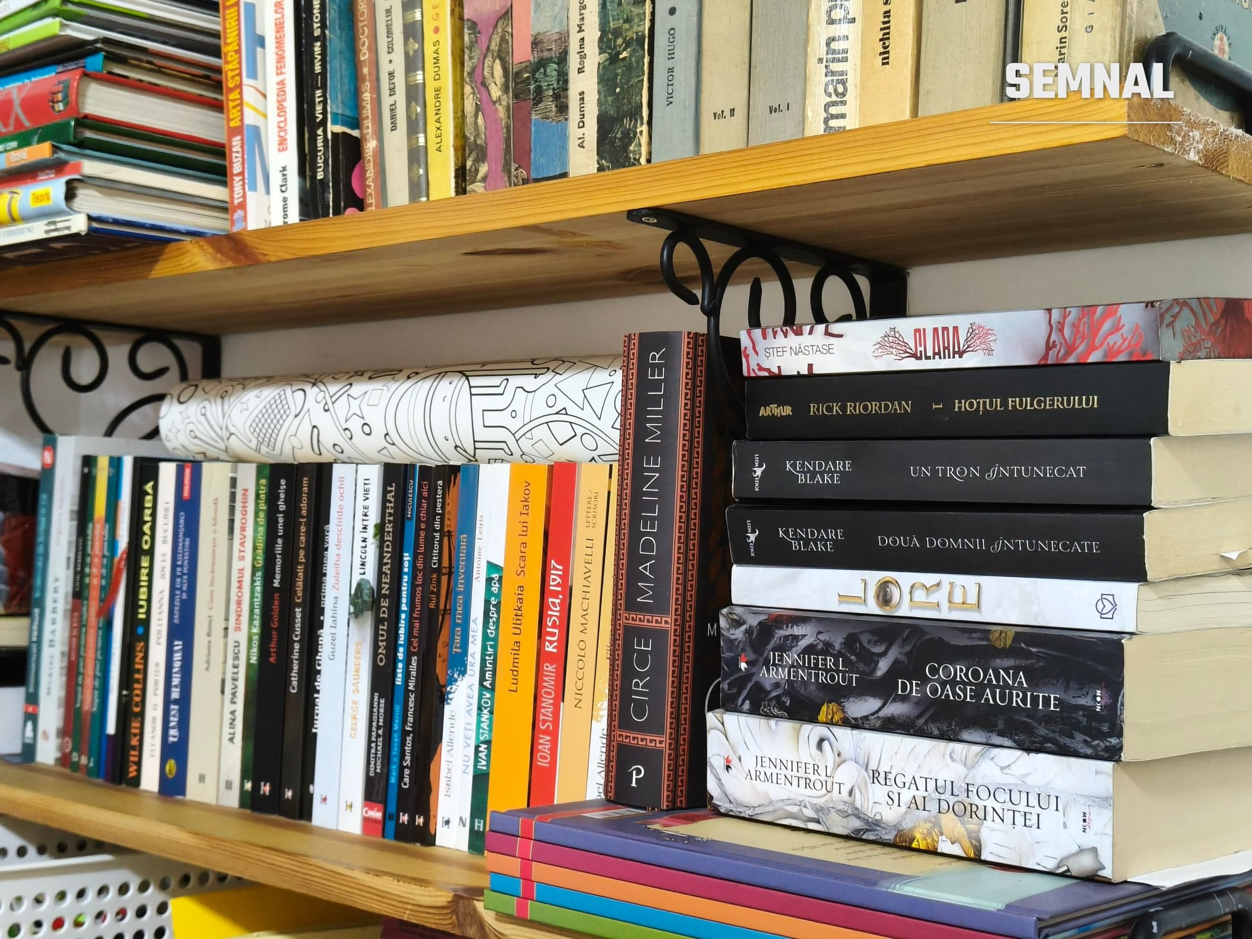 Raft de bibliotecă cu romane traduse în română, între care „Circe” de Madeline Miller și „Hoțul fulgerului” de Rick Riordan