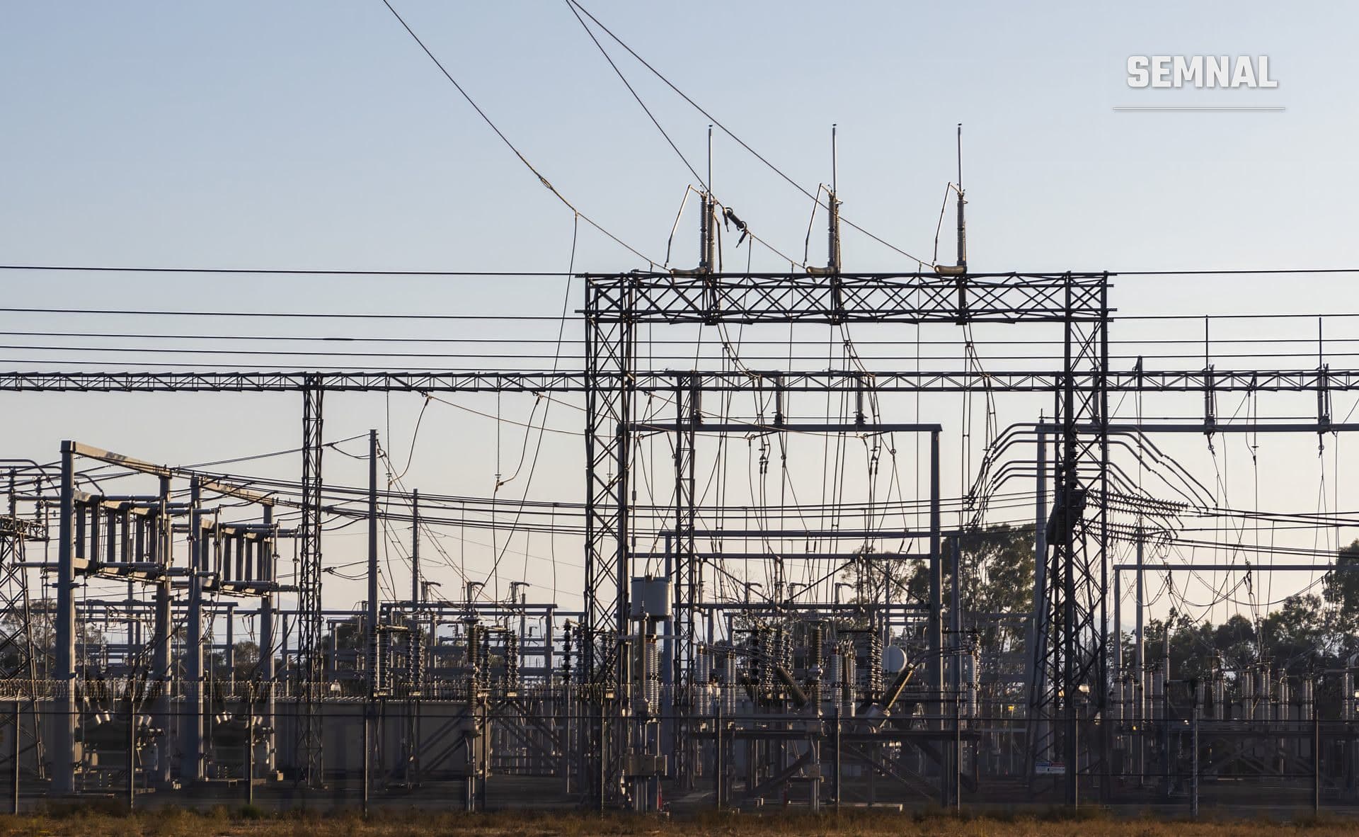Stație electrică de înaltă tensiune cu structuri metalice și linii de transport al energiei, în zori