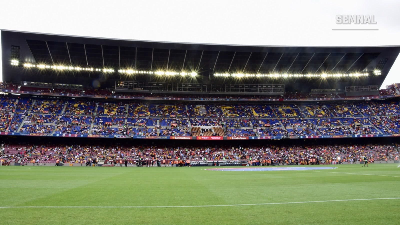 Tribunele stadionului Camp Nou din Barcelona, aproape pline, văzute de pe gazon, cu acoperișul iluminat, în timpul unui meci de La Liga