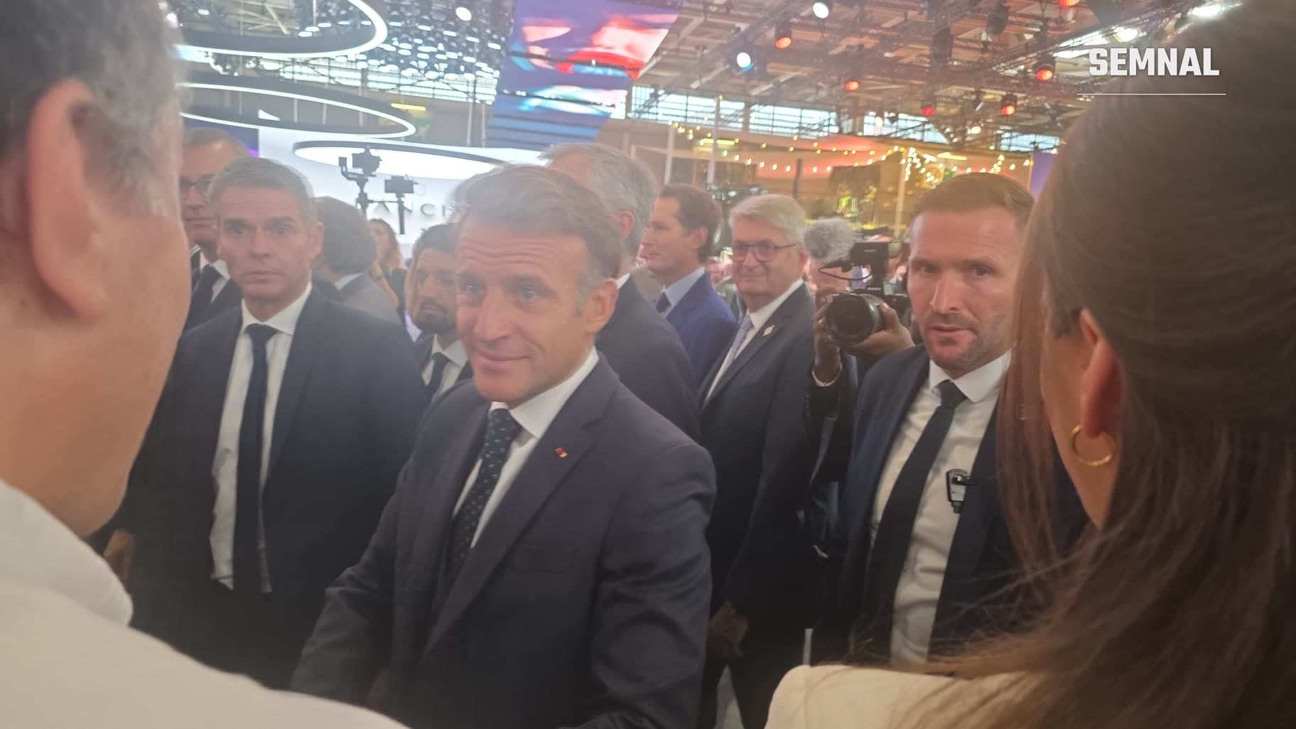 Președintele Franței, Emmanuel Macron, dând mâna cu vizitatorii la Salonul Auto de la Paris 2026, înconjurat de membri ai delegației