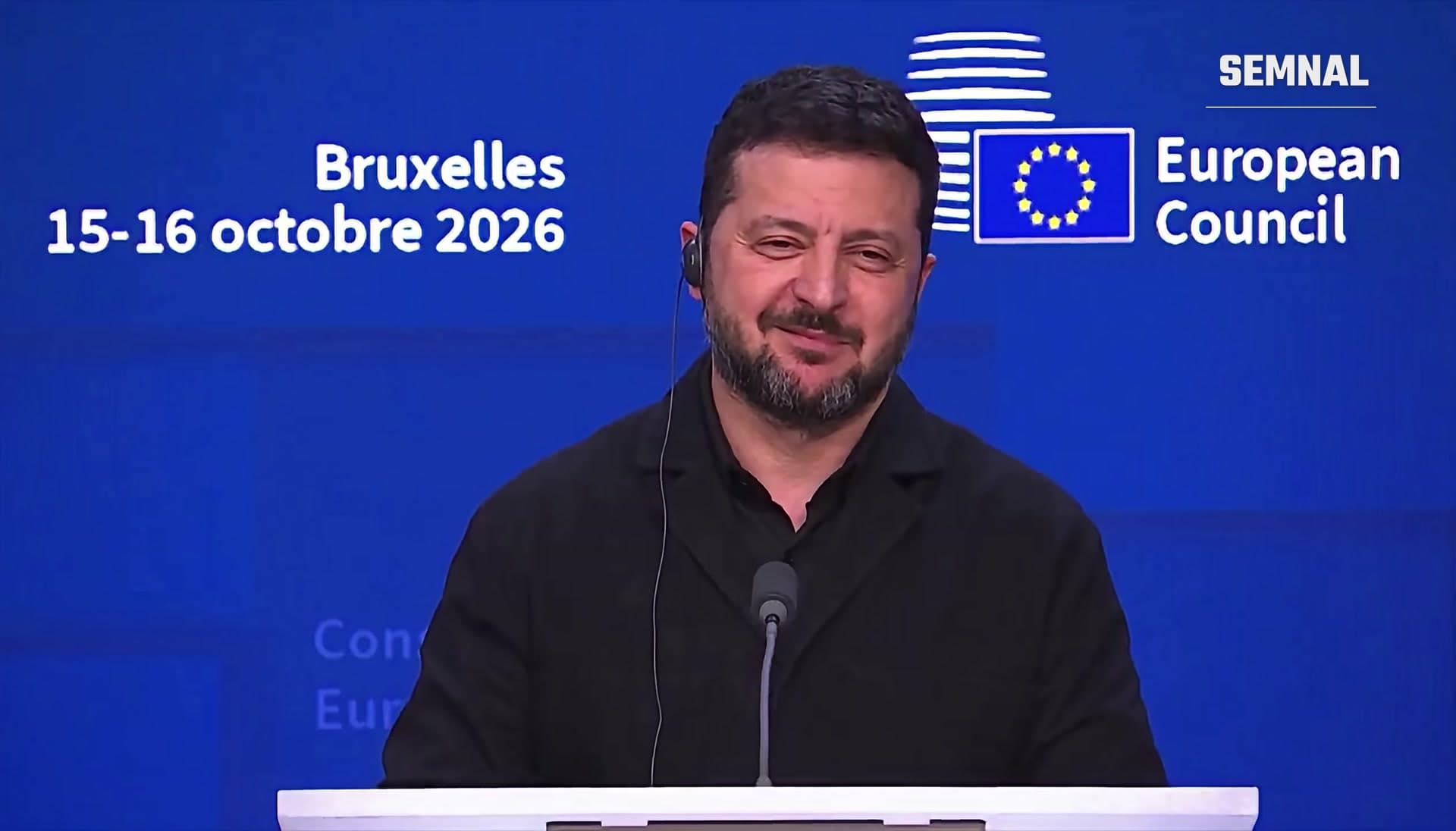 Volodimir Zelenski zâmbește la pupitru, la conferința de presă a Consiliului European de la Bruxelles
