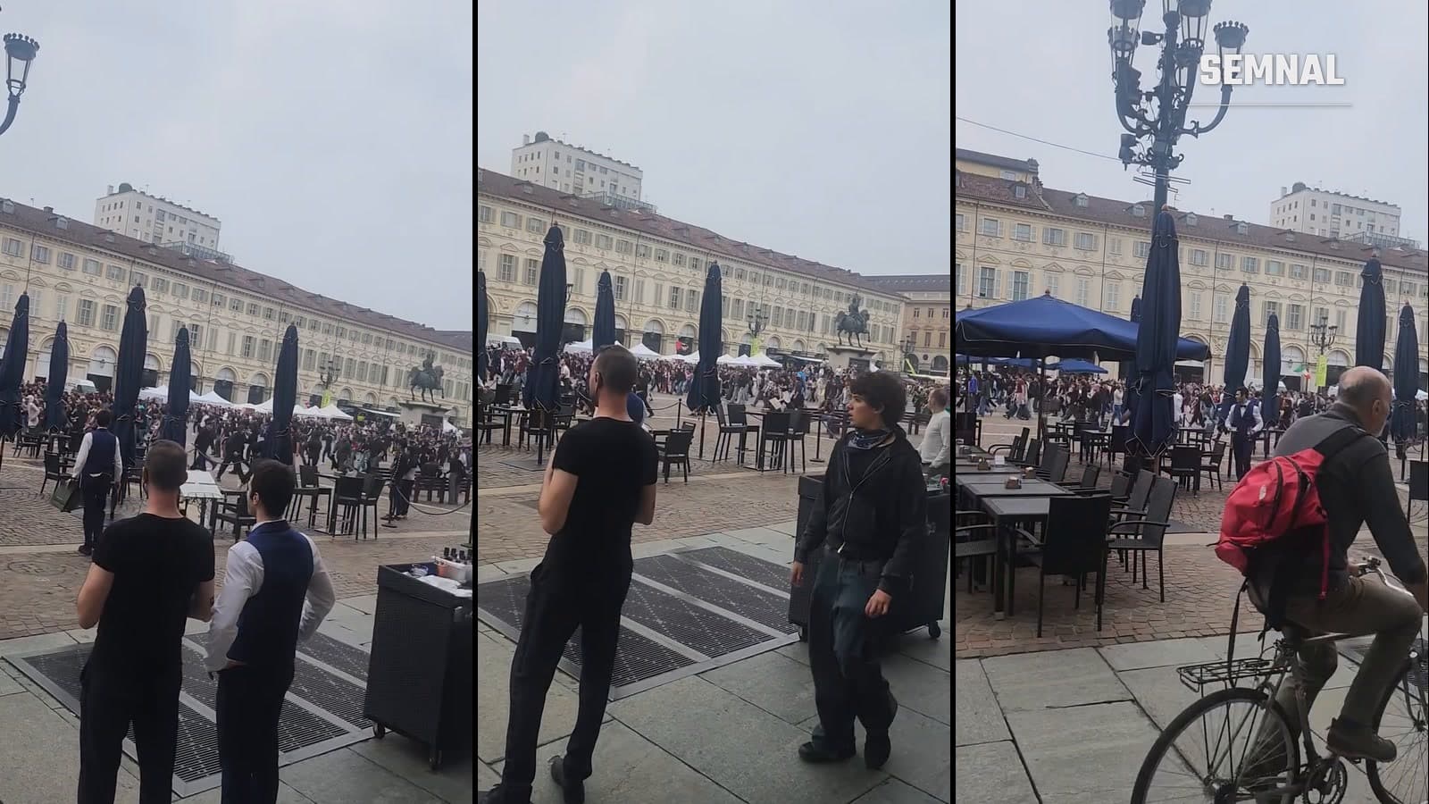 Mulțime de manifestanți care traversează Piazza San Carlo din Torino, privită de pe trotuarul de sub arcade, lângă terasele cafenelelor