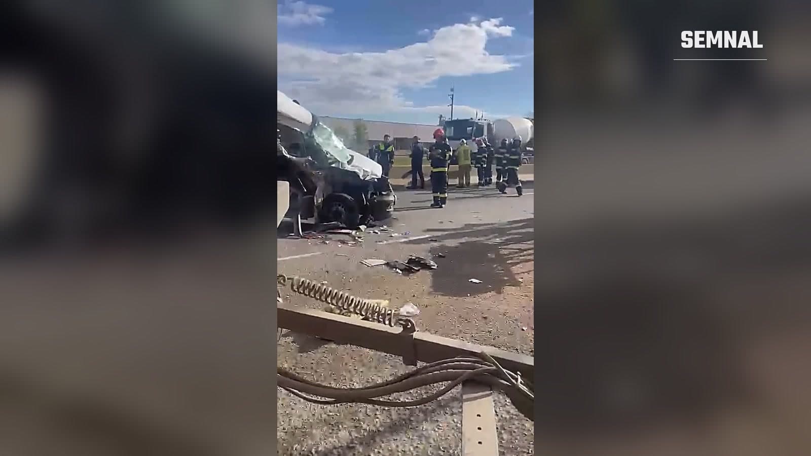 Microbuzul distrus după impactul cu o autobasculantă pe DN 7, la Buftea, cu pompieri și polițiști în fundal