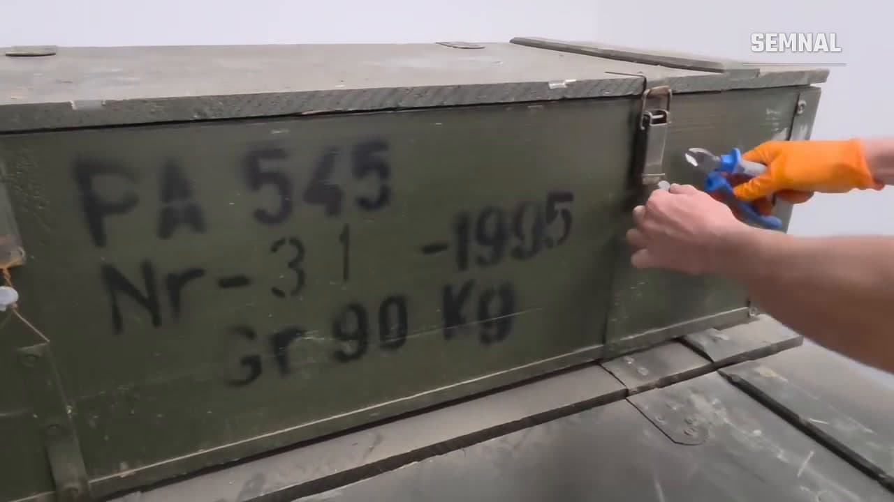 Ladă militară verde, marcată PA 545, Nr. 31, 1995 și 90 kg, deschisă de un angajat al firmei Arms of America