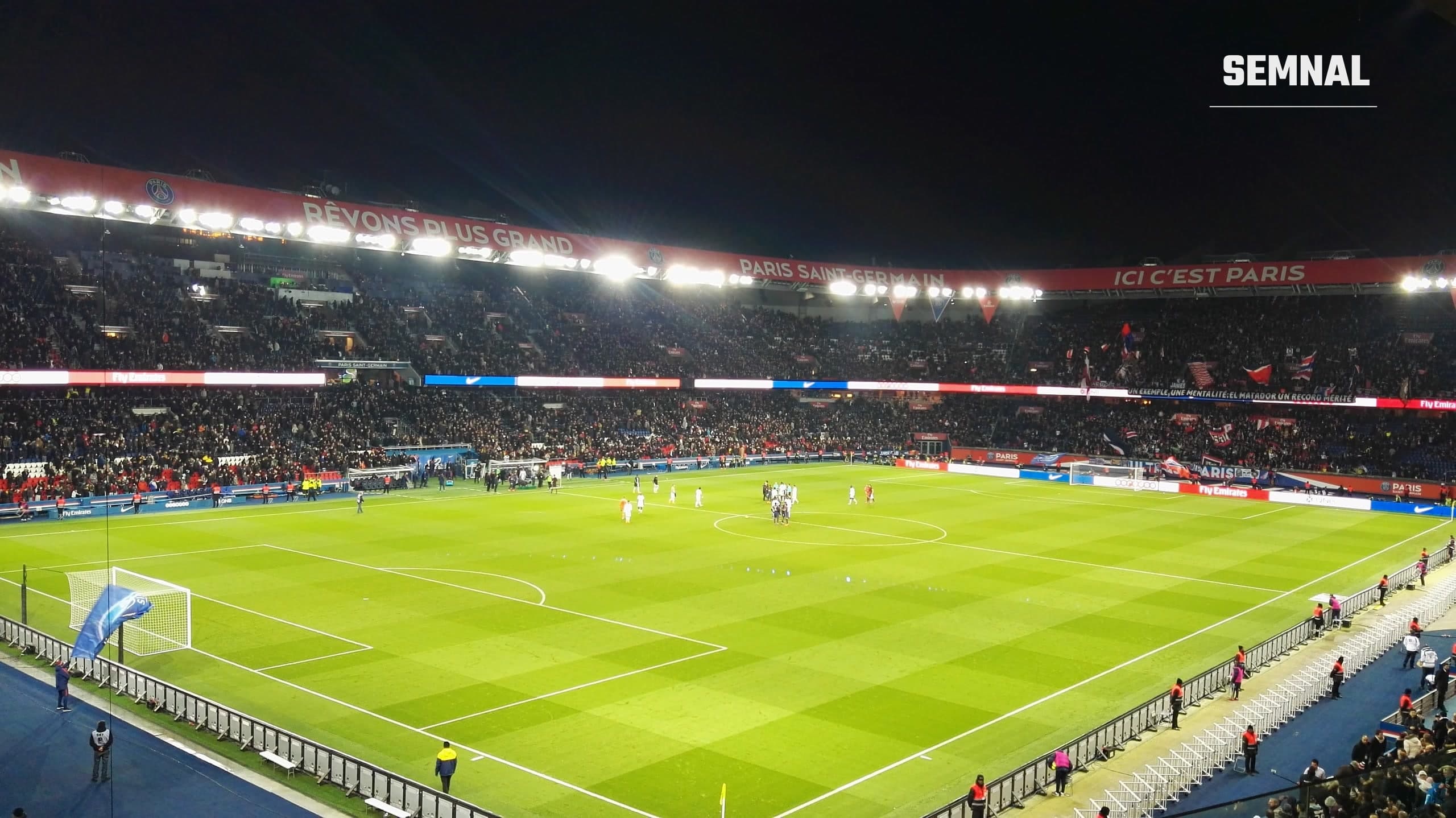 Vedere de ansamblu a stadionului Parc des Princes din Paris, noaptea, în timpul unui meci al echipei Paris Saint-Germain, cu tribunele pline și bannerele clubului