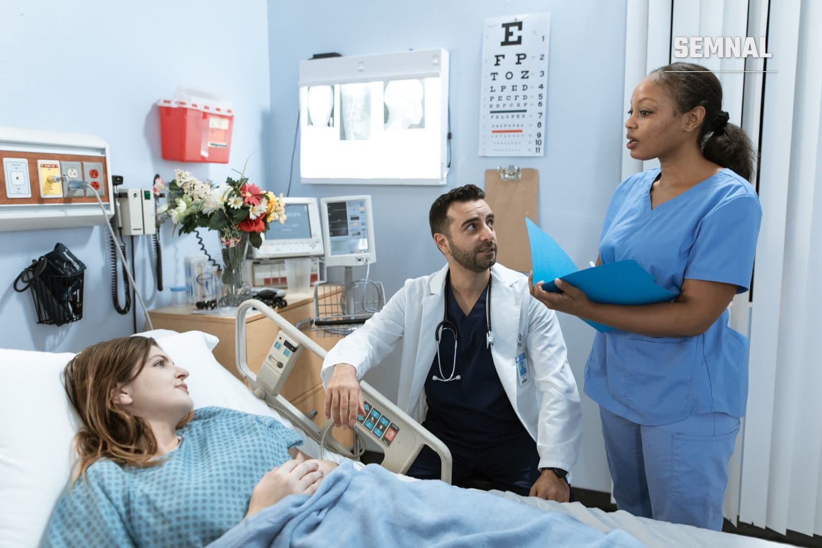 Medici și o asistentă discută despre tratamentul unui pacient într-un salon de spital