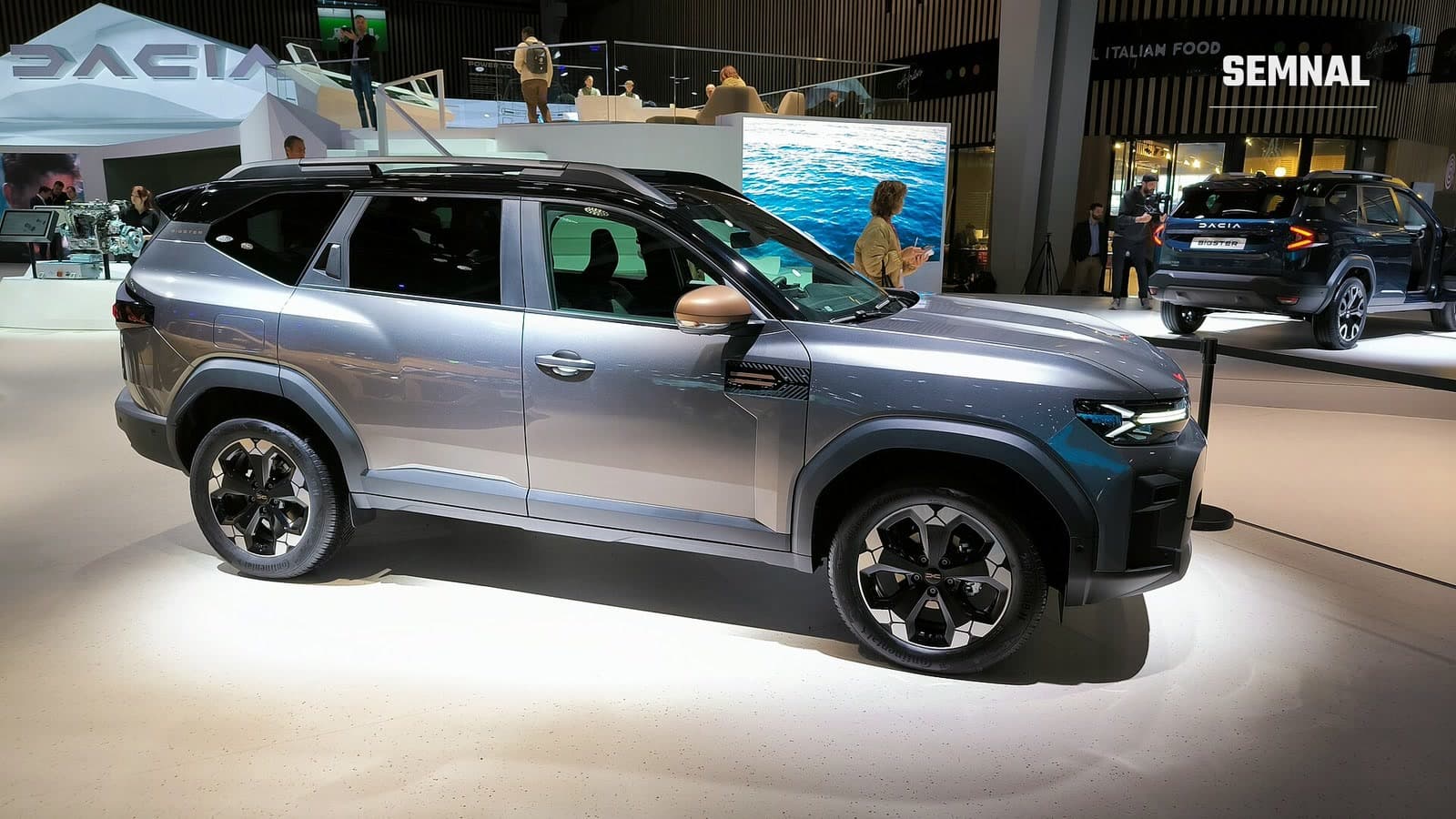 Dacia Bigster gri, văzut din lateral-față, expus pe standul mărcii la Salonul Auto de la Paris, în octombrie 2024