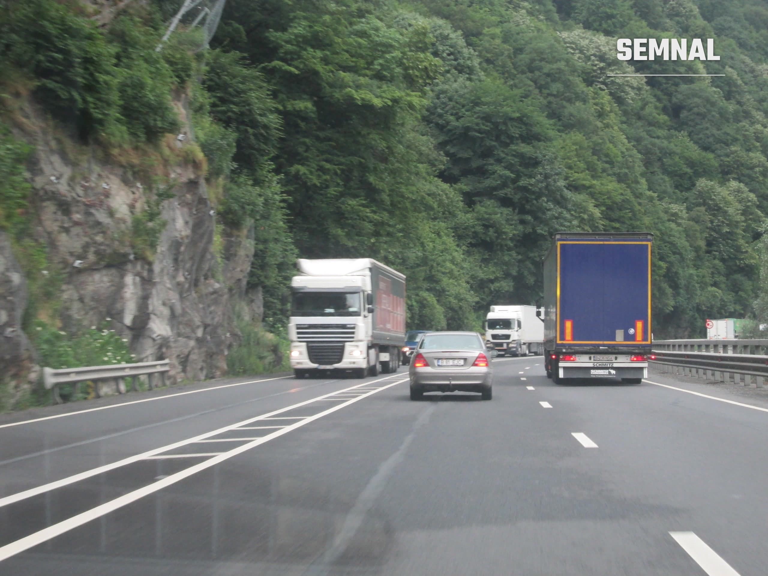 Sector de drum cu bandă suplimentară pe DN7, în defileul Oltului, cu un autocamion și un autoturism în trafic. Imagine ilustrativă