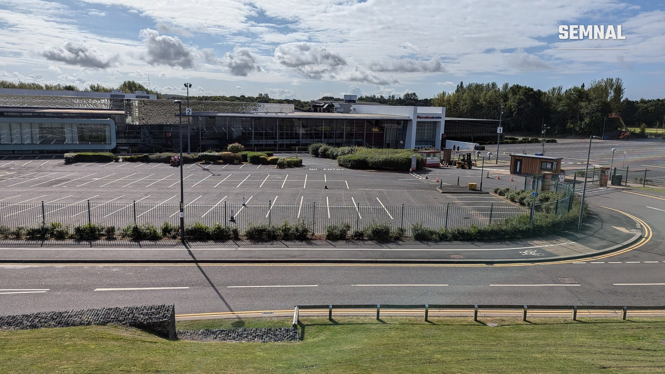 Clădirea Telford International Centre din Anglia, văzută de peste drum, cu parcarea goală în față și cer cu nori