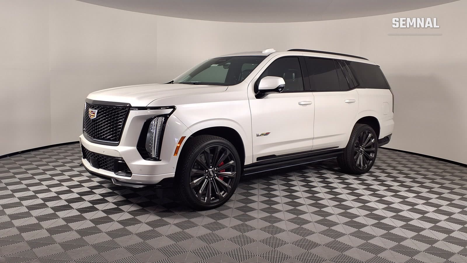 Cadillac Escalade-V alb, văzut din față și din lateral, într-un showroom cu pereți deschiși și pardoseală în carouri gri