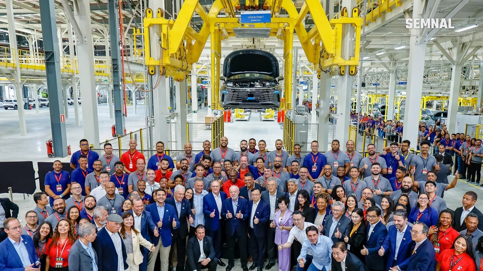 Muncitori și oficiali pozează în hala de asamblare a fabricii BYD din Camaçari, Bahia, la inaugurarea din 9 octombrie 2025; în fundal, o caroserie pe linia de șasiu