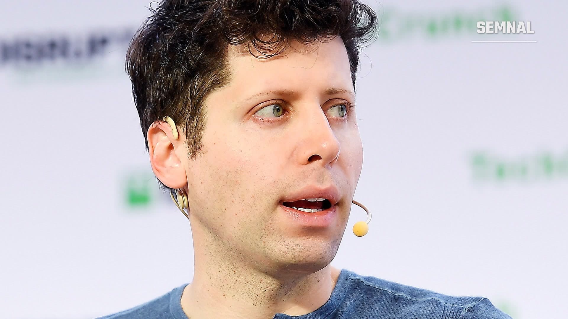Sam Altman, directorul general al OpenAI, vorbind pe scena conferinței TechCrunch Disrupt, cu un microfon atașat la ureche