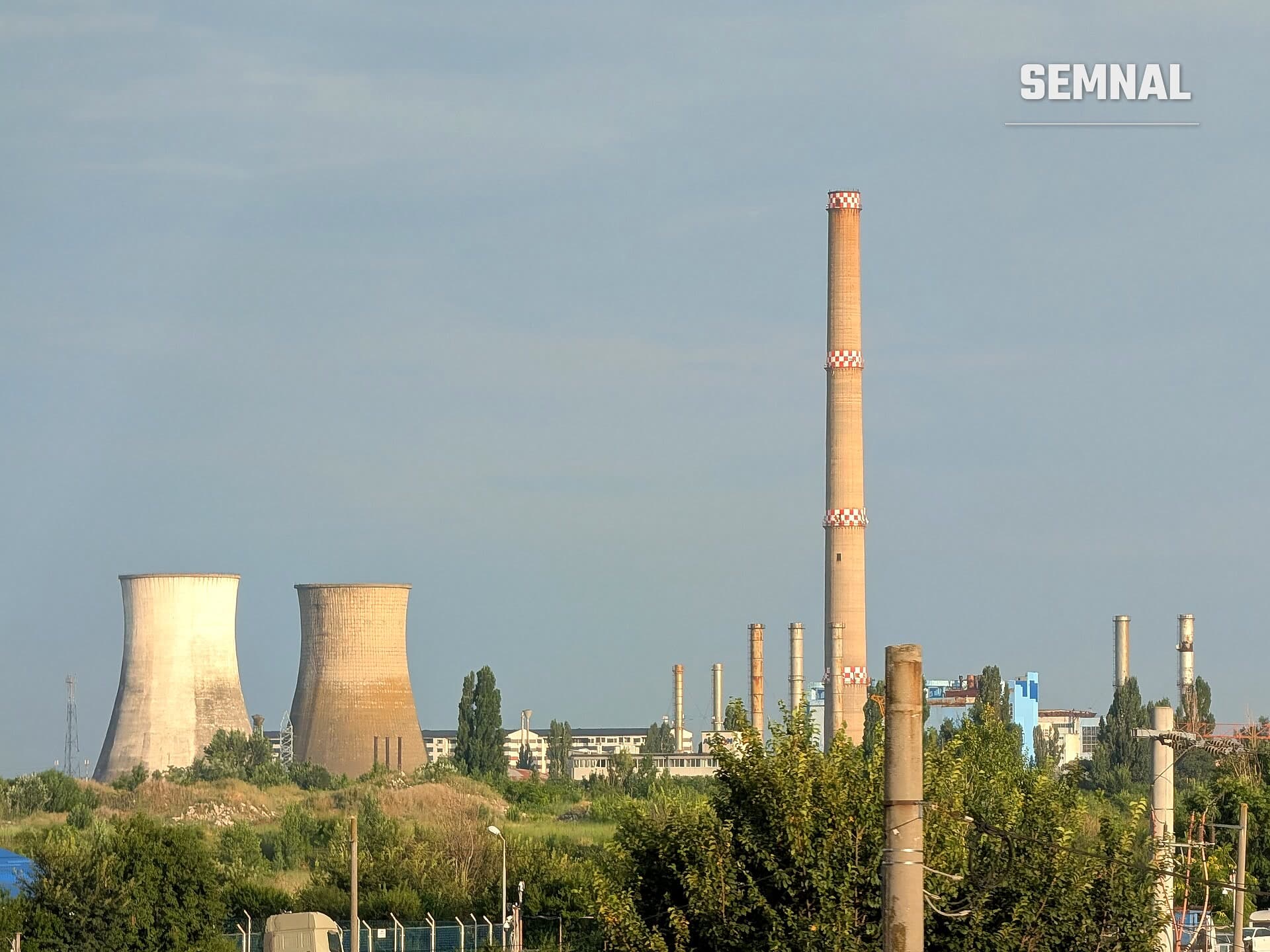 Două turnuri de răcire și un coș înalt, alb cu roșu, ale centralei CET București Vest, văzute de la distanță
