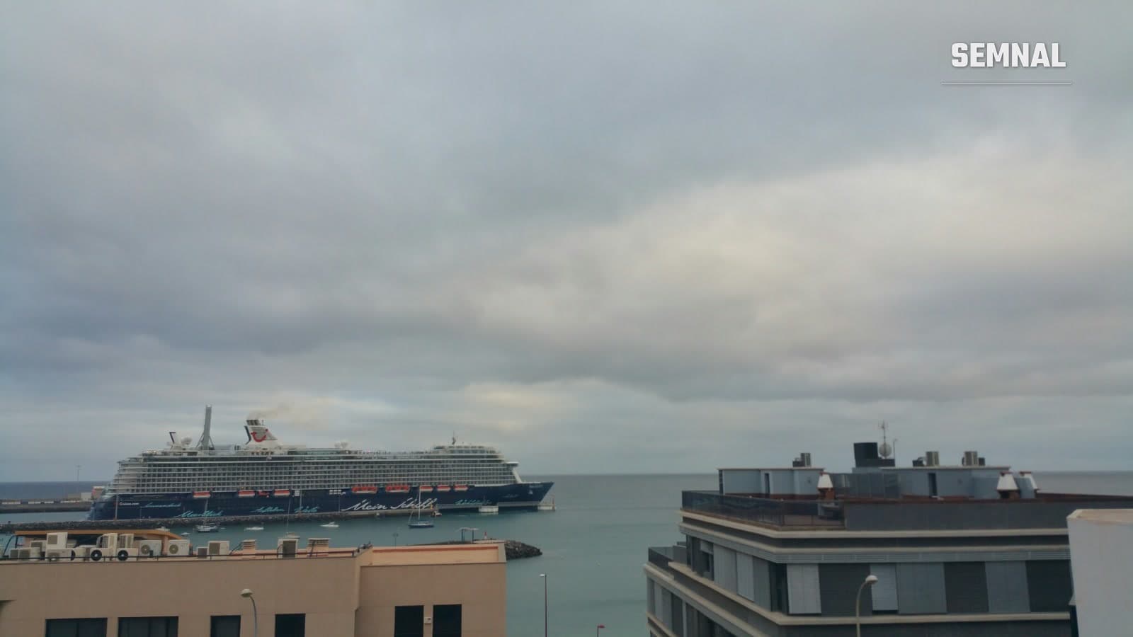 Navă de croazieră cu inscripția Mein Schiff, acostată într-un port, sub un cer acoperit de nori