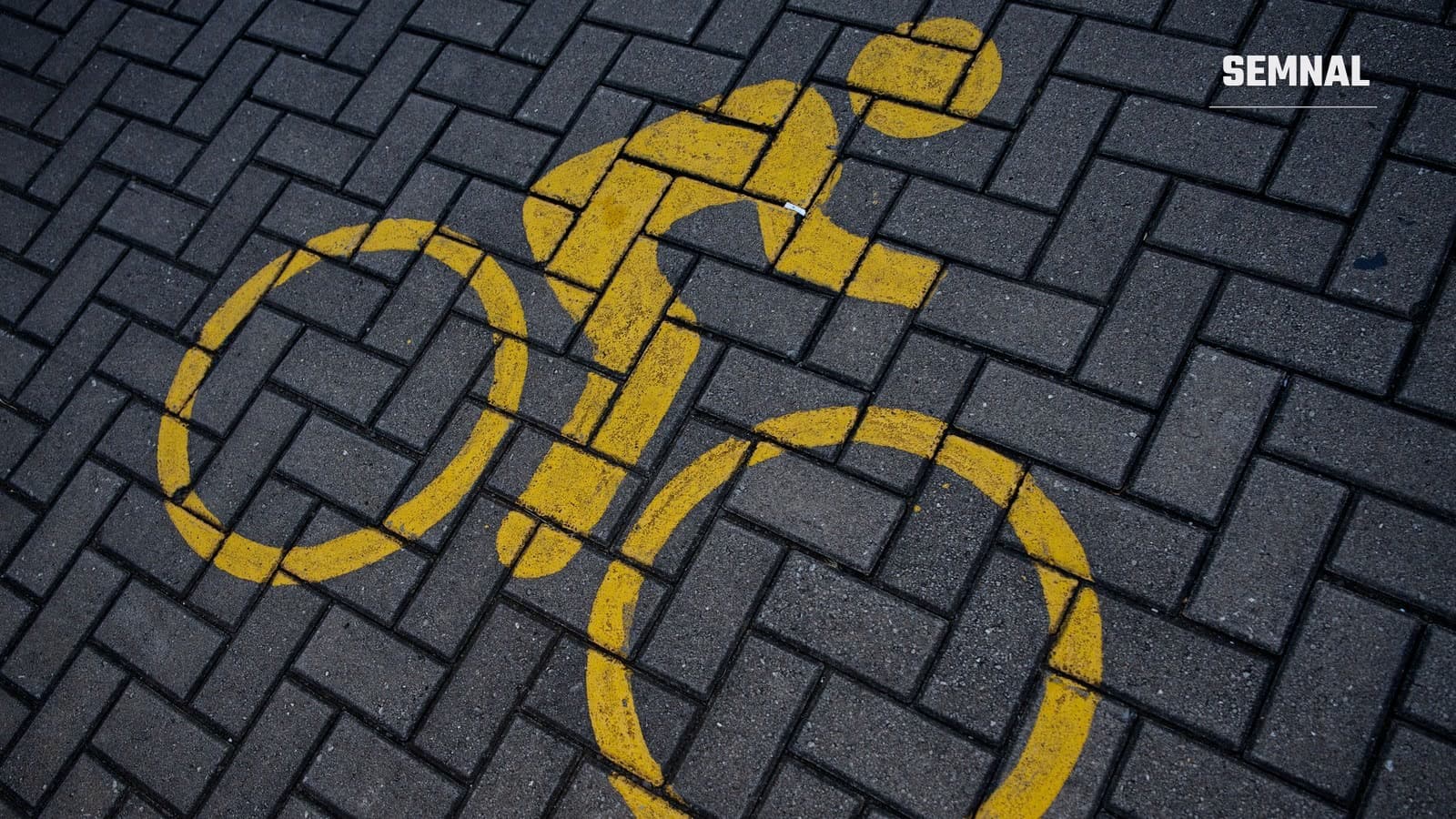 Simbol galben de bicicletă pictat pe pavajul gri al unei străzi, vedere de sus