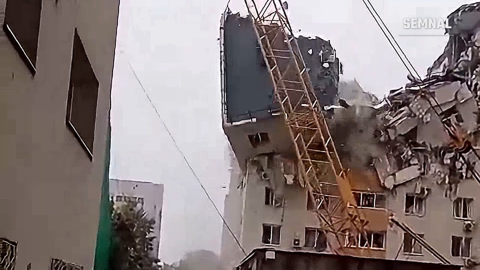 Etajele superioare ale blocului din Rahova se desprind în timpul demolării controlate, lângă brațul unei macarale