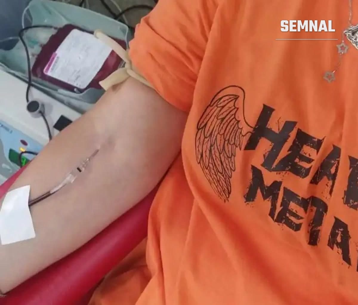 Imagine ilustrativă dintr-un cadru medical: brațul unei persoane cu acul fixat cu plasture, o pungă cu sânge și un aparat în fundal, într-un scaun roșu. (Foto: arhivă personală)