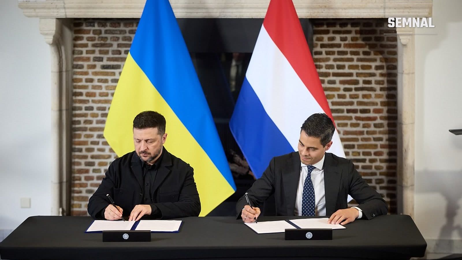 Volodimir Zelenski și premierul olandez Rob Jetten semnează documente la o masă, în fața drapelelor Ucrainei și Țărilor de Jos, în aprilie 2026