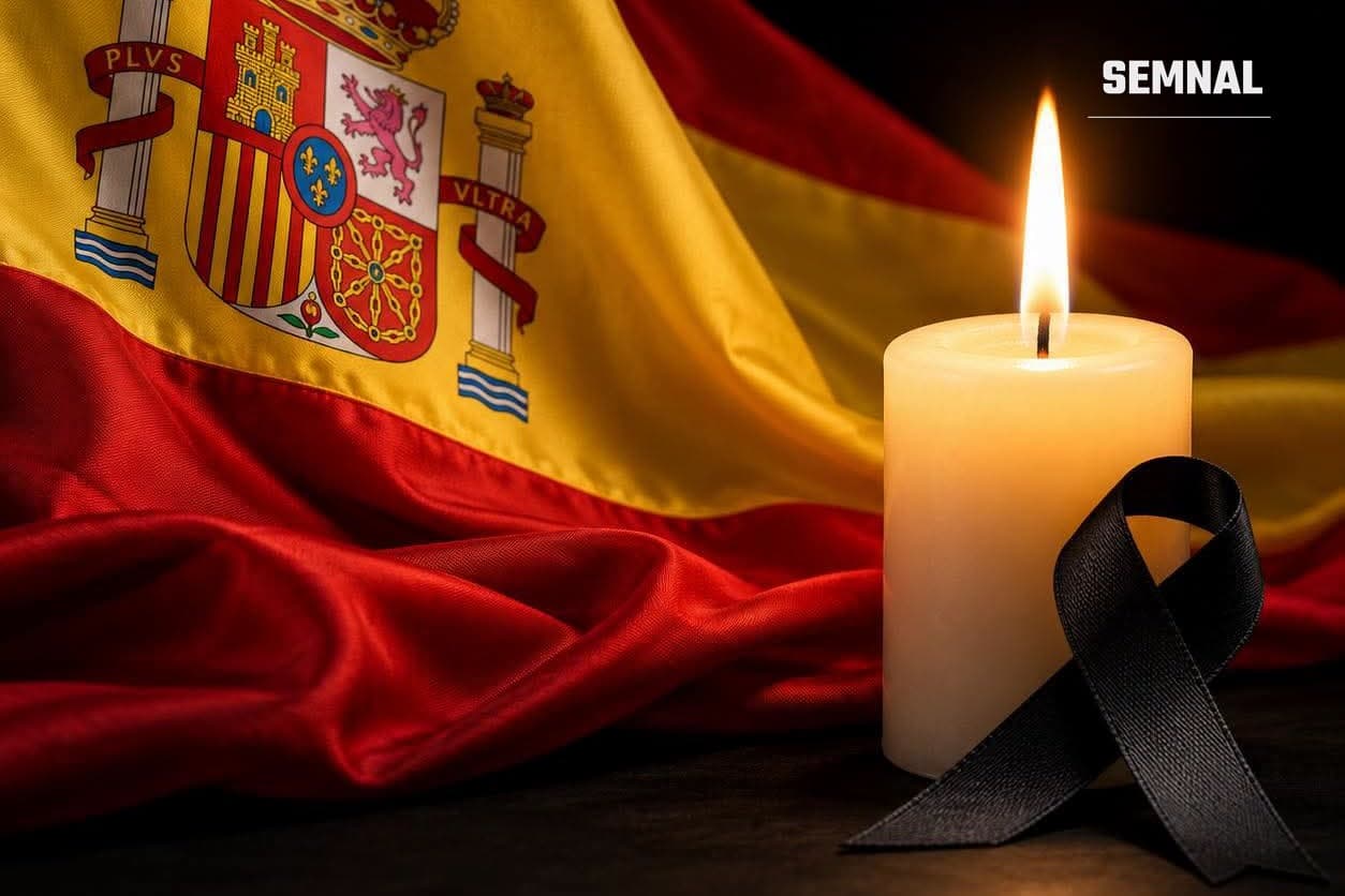 O lumânare aprinsă și o panglică neagră de doliu, în fața drapelului Spaniei