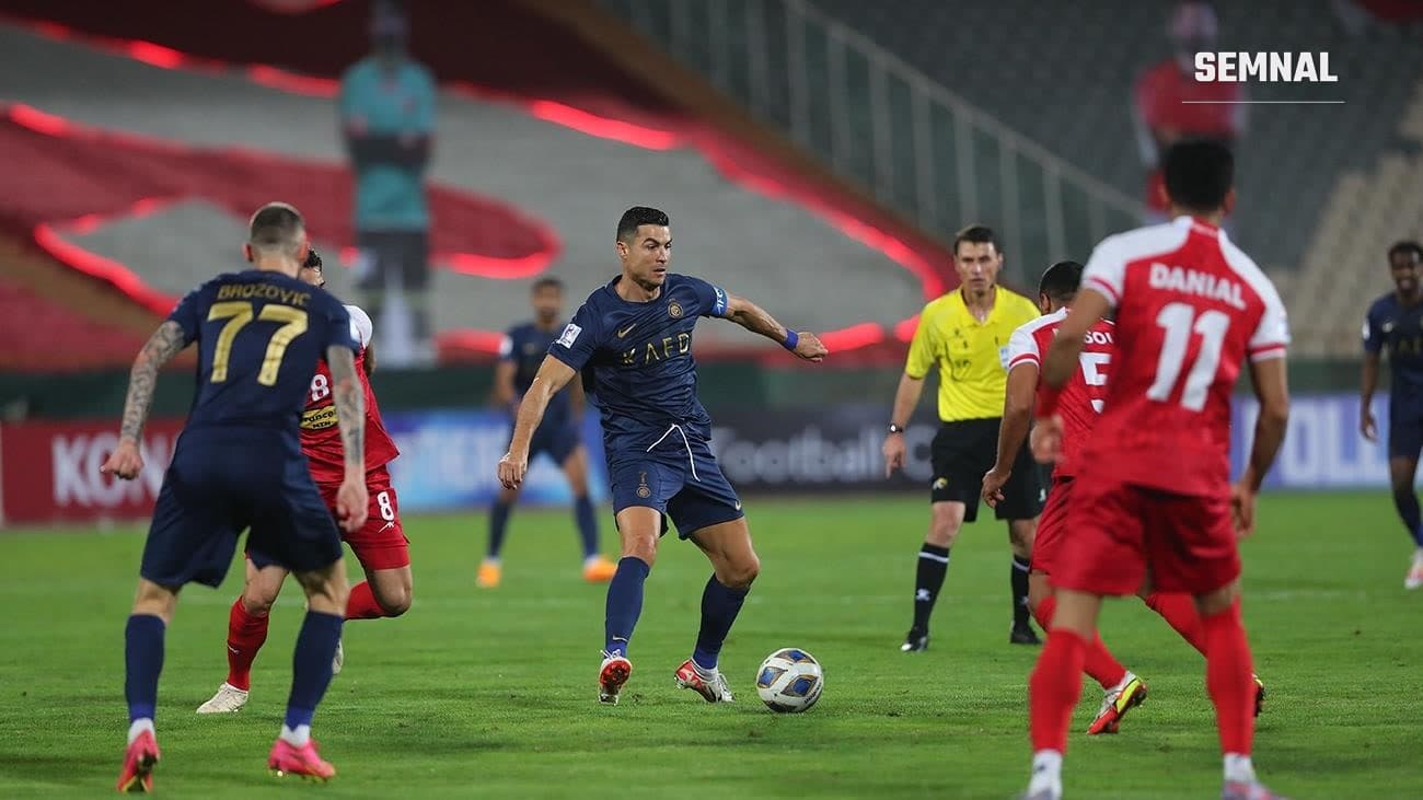 Cristiano Ronaldo, în echipamentul lui Al Nassr, conduce mingea printre jucătorii lui Persepolis.