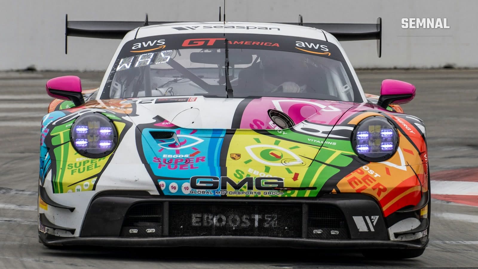 Fotografie ilustrativă: Porsche 911 GT3 de curse, văzut din față pe circuit, cu caroserie colorată și sigle de sponsori, același tip de mașină ca al lui Hartog
