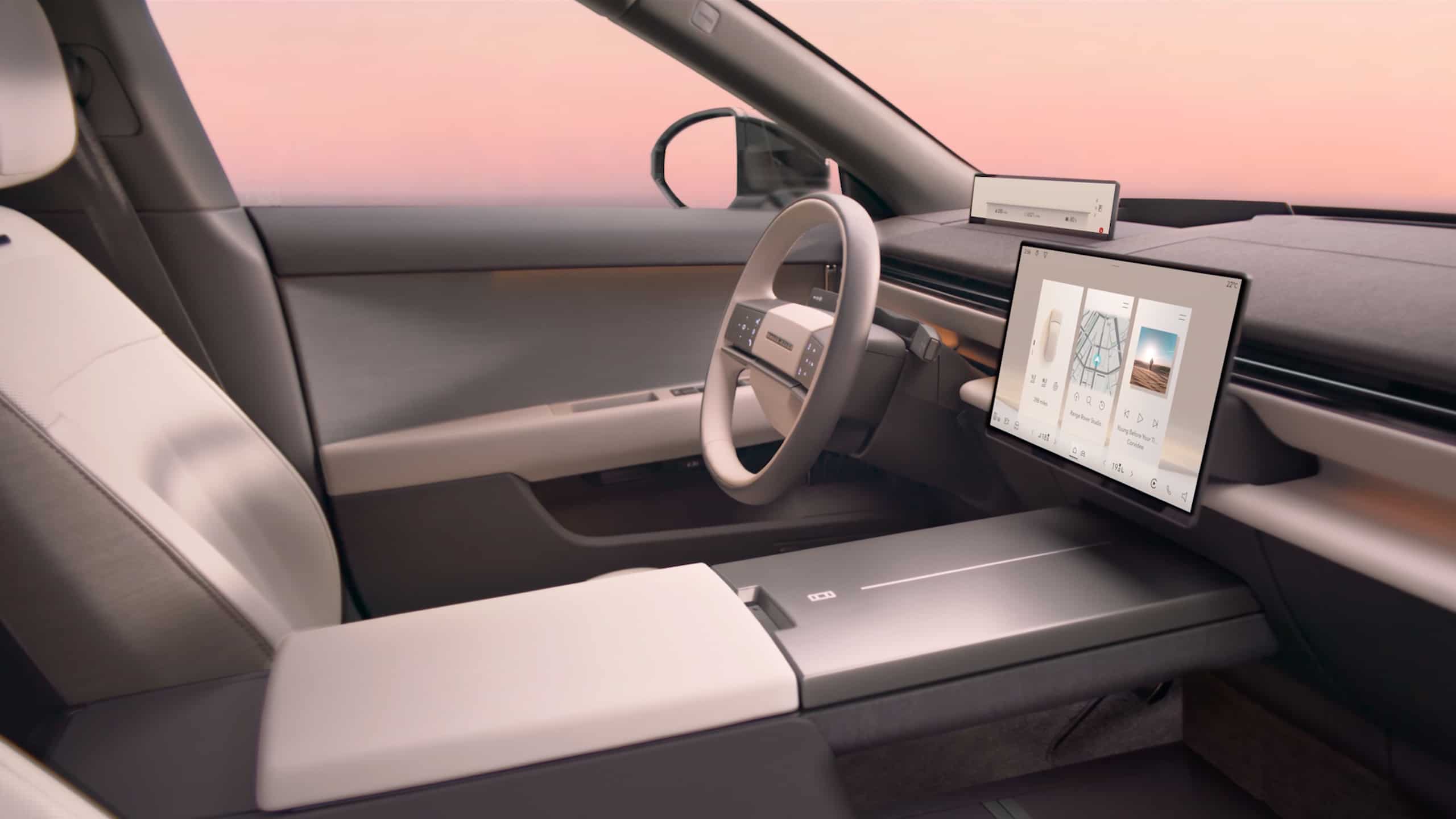 Interiorul conceptului Range Rover Electric 2027 cu scaune ergonomice gri-crem, ecran tactil mare pe tablă de bord, volan modern și vedere prin parbriz către crepusculul roz pe orizont.