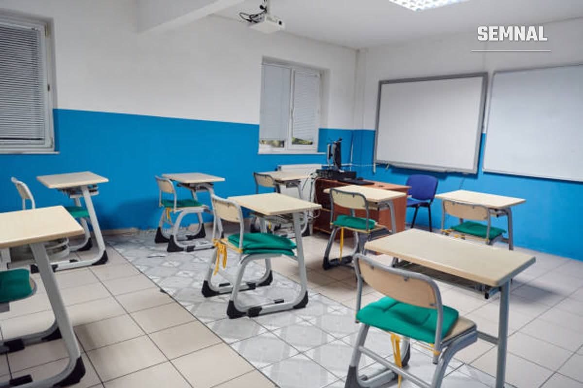 Sala de clasă fără elevi, doar cu banci, scaune și tabla goală.