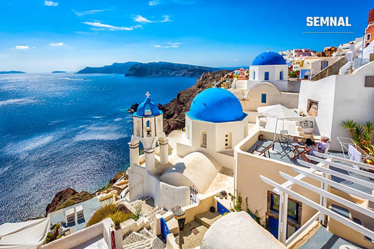 Imagine din Grecia,  biserică, cer senin și marea albastră.