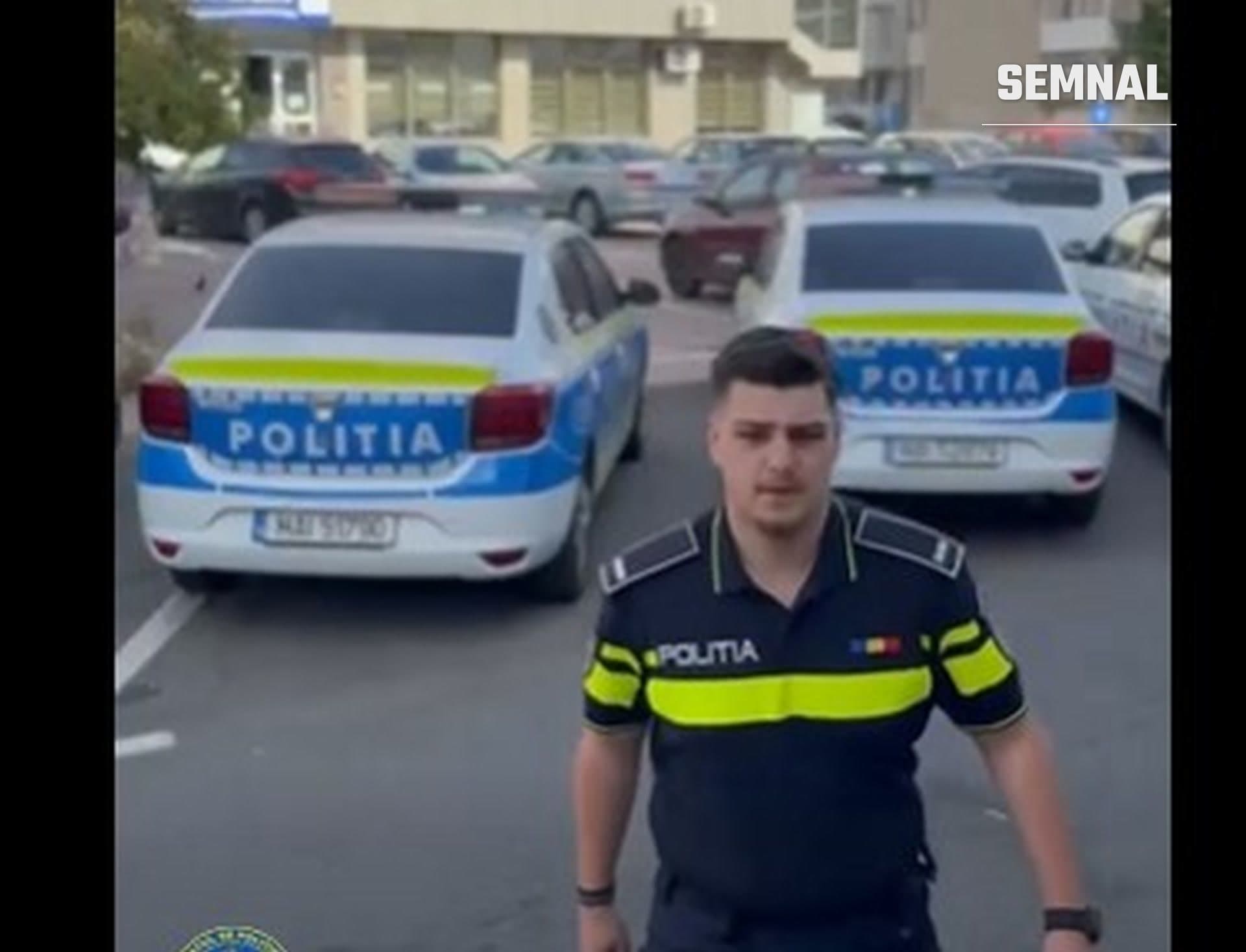 În imagine este polițistul Alin Gabriel Matei, alături de două mașini de poliție staționate.