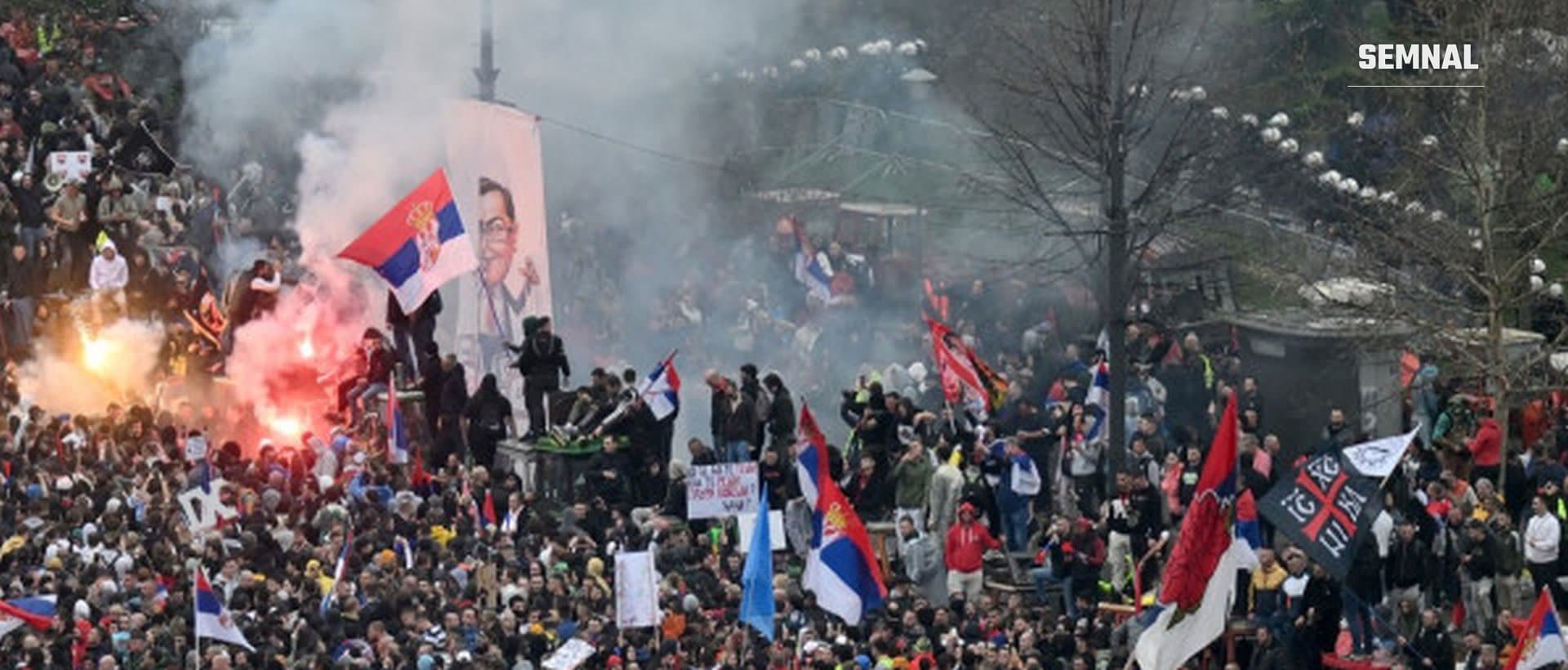 În imagine sunt mii de oameni care protestează în Serbia cu steaguri.
