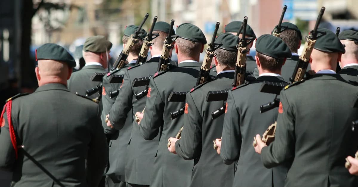 Un grup de soldați în uniforme verzi și berete verzi mărșăluiesc, fiecare purtând o armă pe umăr.