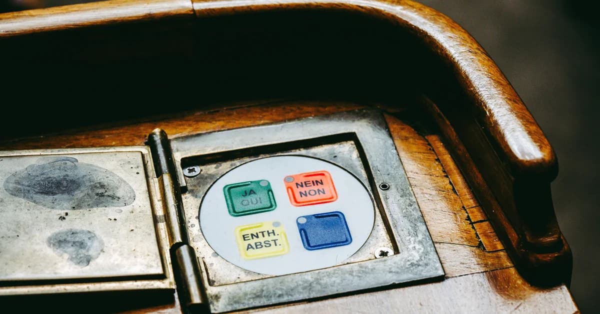 Butonieră de votare într-un obiect de mobilier din lemn, cu butoane colorate pentru "Da", "Nu" și "Abținere".