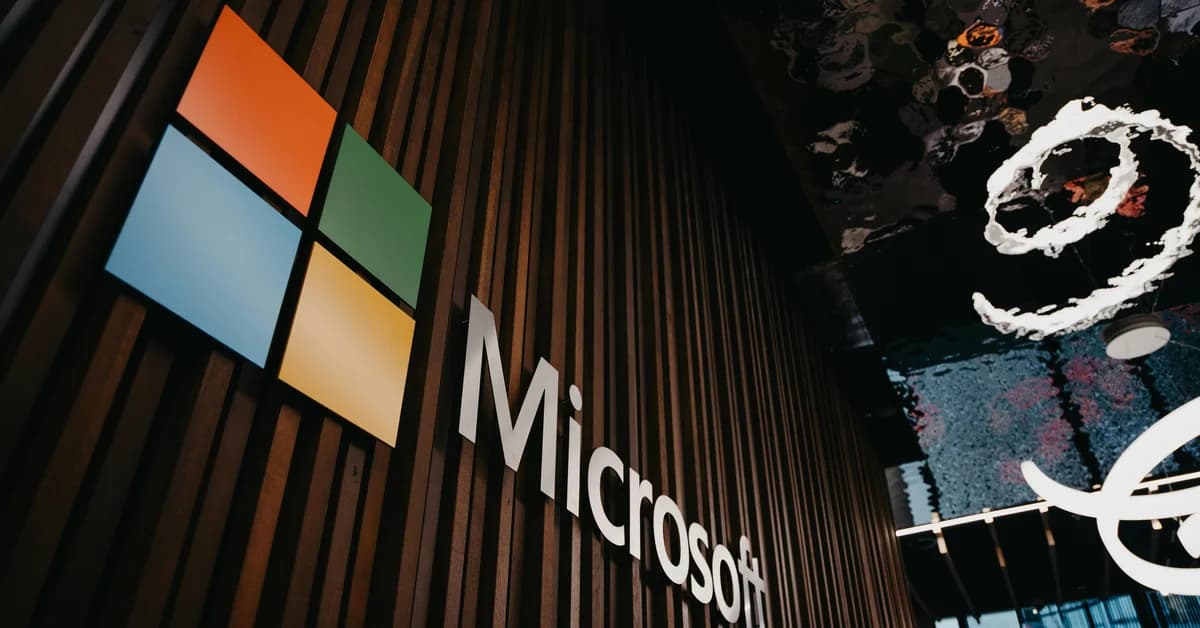 Logo-ul Microsoft pe un perete din lemn, iluminat, cu un plafon de design modern și reflexii.