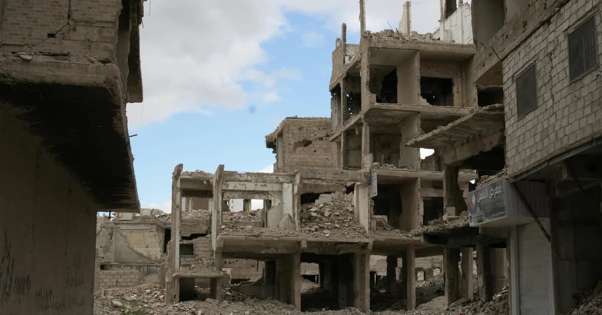 Clădiri distruse, în ruine, într-un oraș afectat de conflict, cu cer parțial albastru pe fundal.