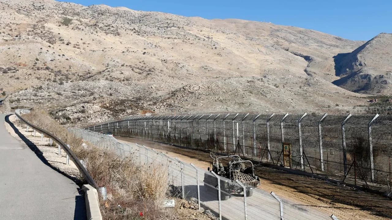 Gard de securitate cu sârmă ghimpată și clădiri militare în teren deșert, având dealuri stâncoase în fundal - ilustrând infrastructura de control la frontiera Quneitra dintre Israel și Siria.