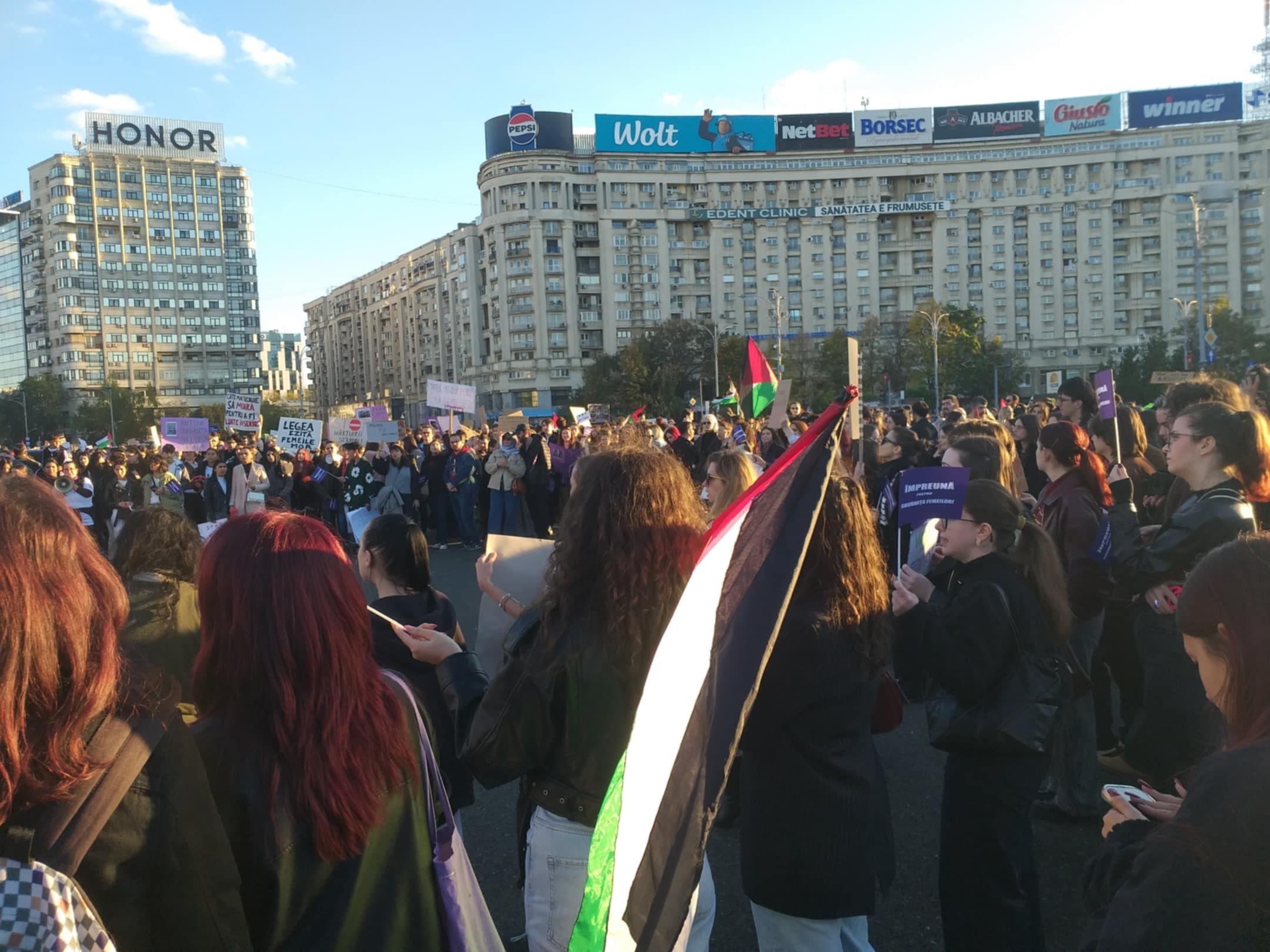 Protest cu mii de participanți la Madrid împotriva crizei locuințelor, oameni ținând steaguri și pancarte în piață publică, lângă blocuri de locuințe și semne comerciale