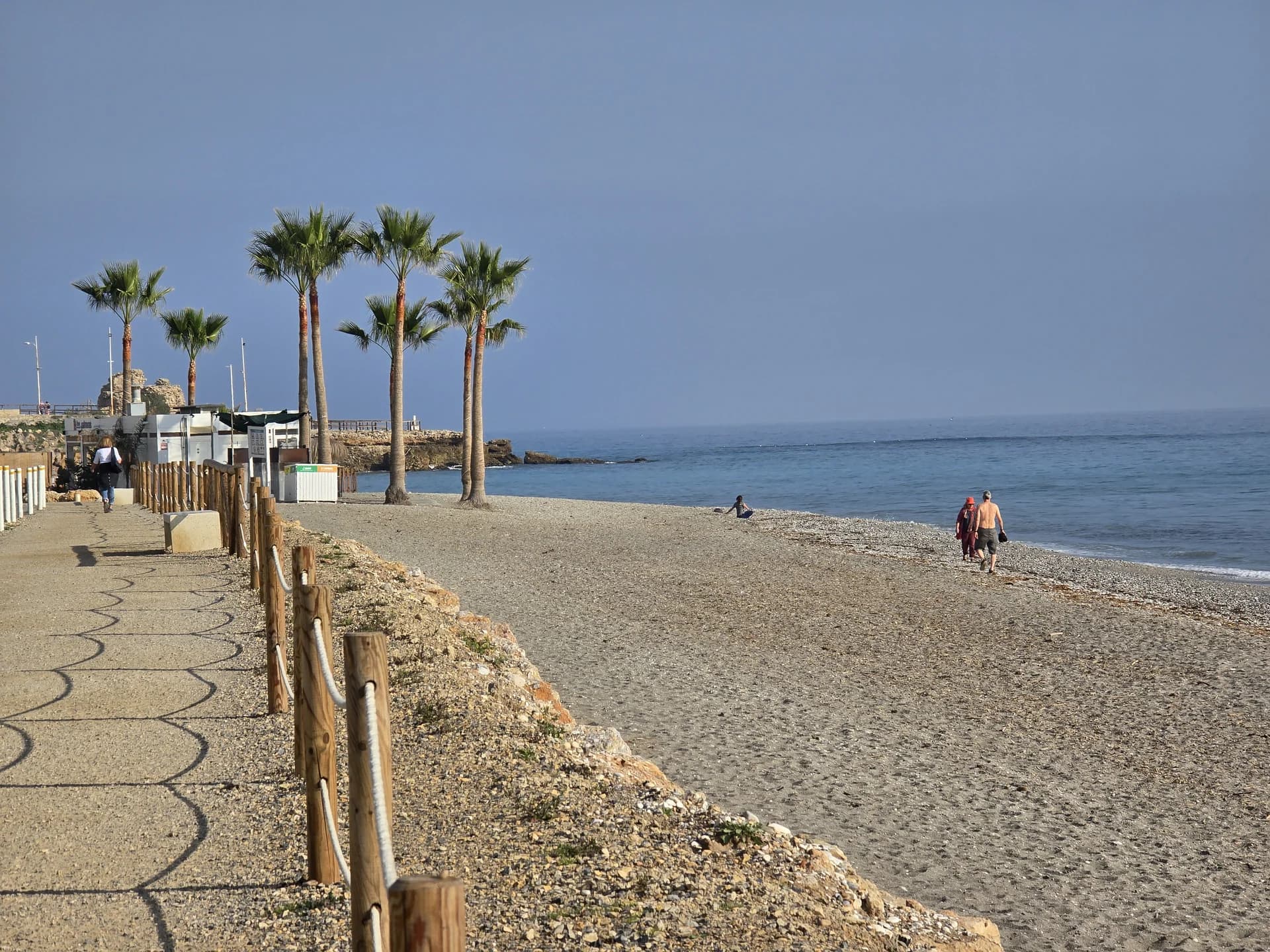Plajă pe litoralul mediteranean spaniol, cu palmieri și promenadă, dimineața devreme