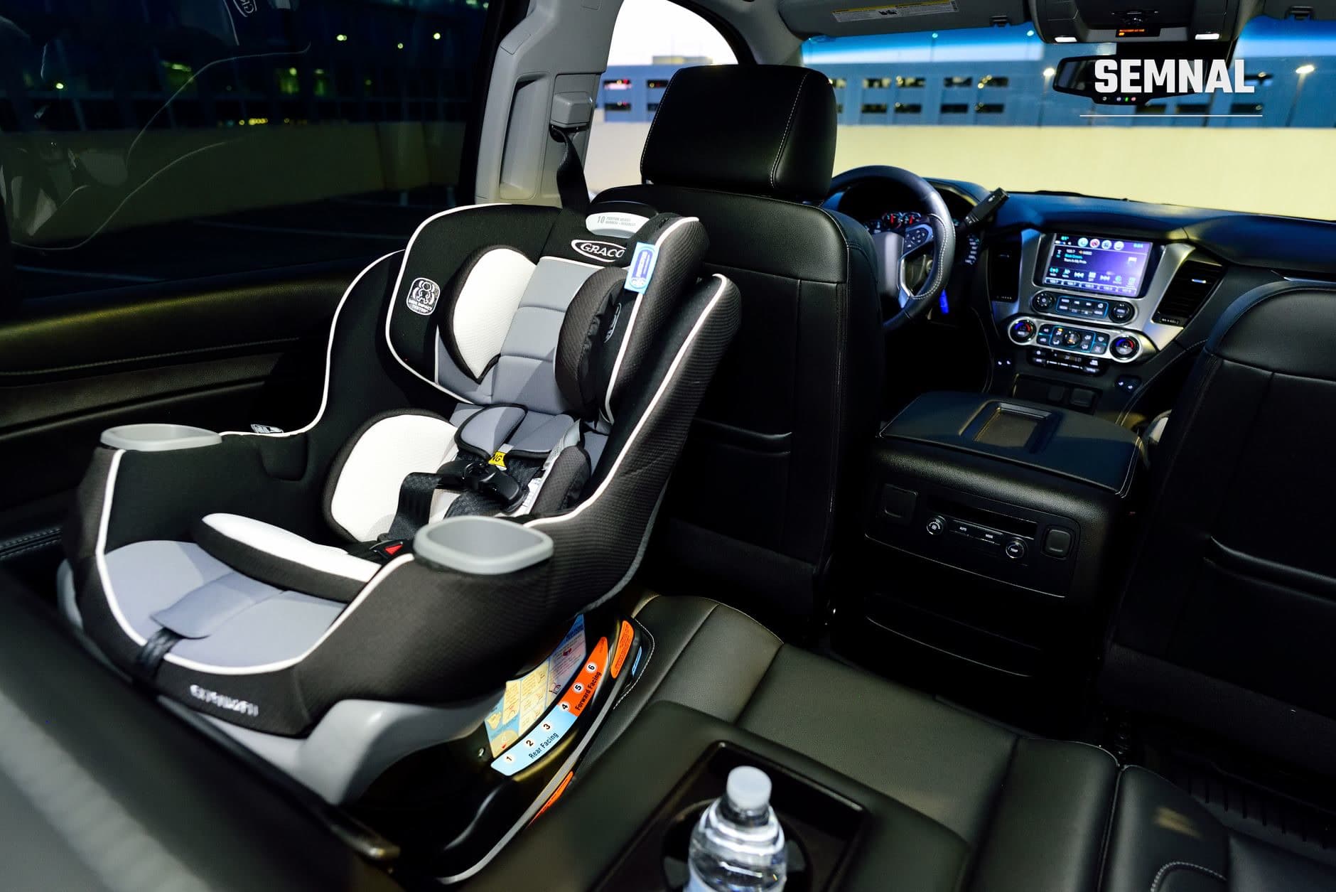 Scaun auto pentru copii Graco cu design alb-negru instalat in bancheta din spate a unui vehicul, echipat cu bretele de siguranta si pernute de sprijin, in interior modern de masina
